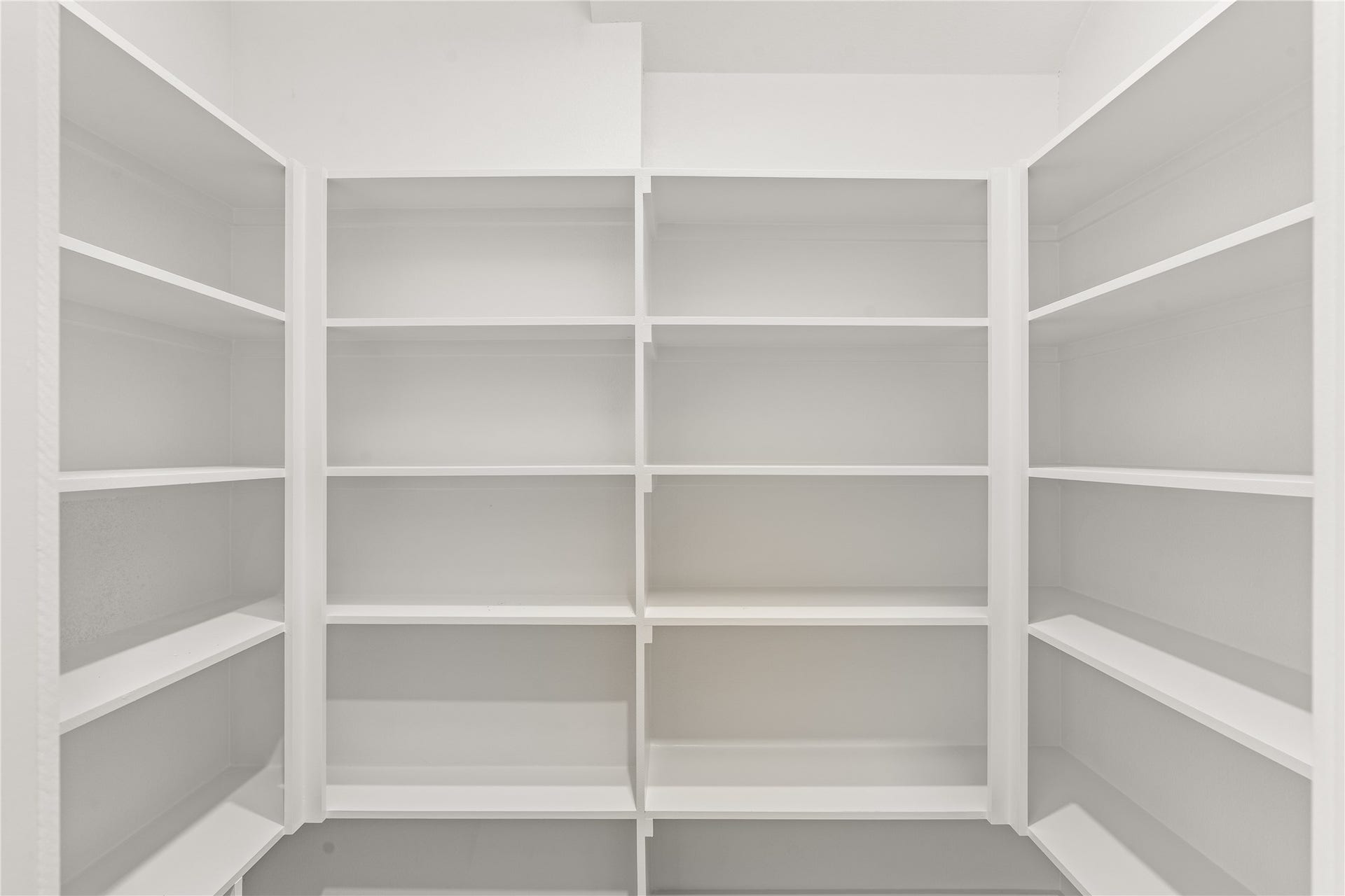 The walk-in pantry. Built-in shelving on three walls, floor to ceiling, so the kitchen cabinets stay clean.