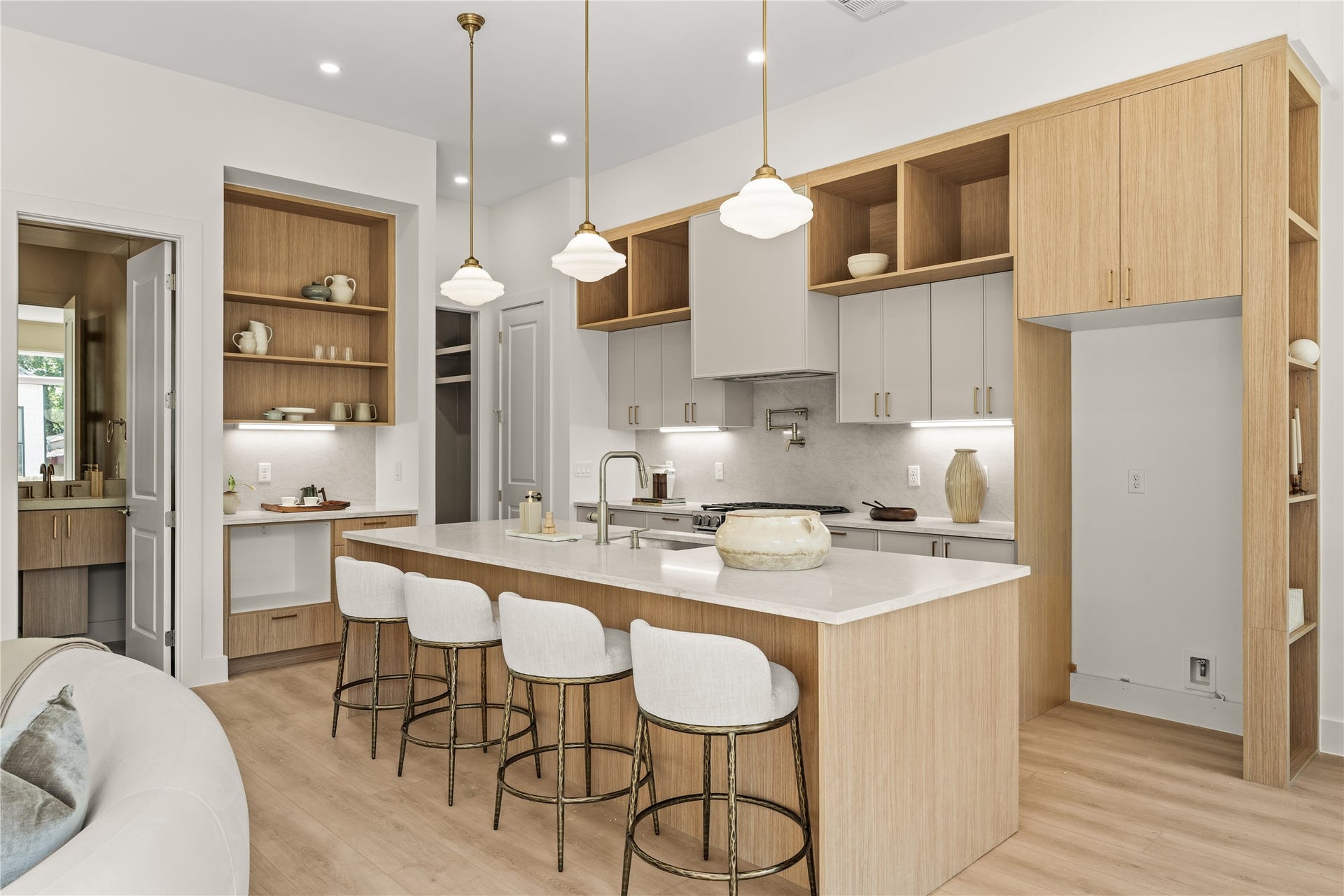 The kitchen. Oversized quartz island with seating for four, cabinets stacked to the ceiling, and a coffee bar tucked around the corner in warm wood.