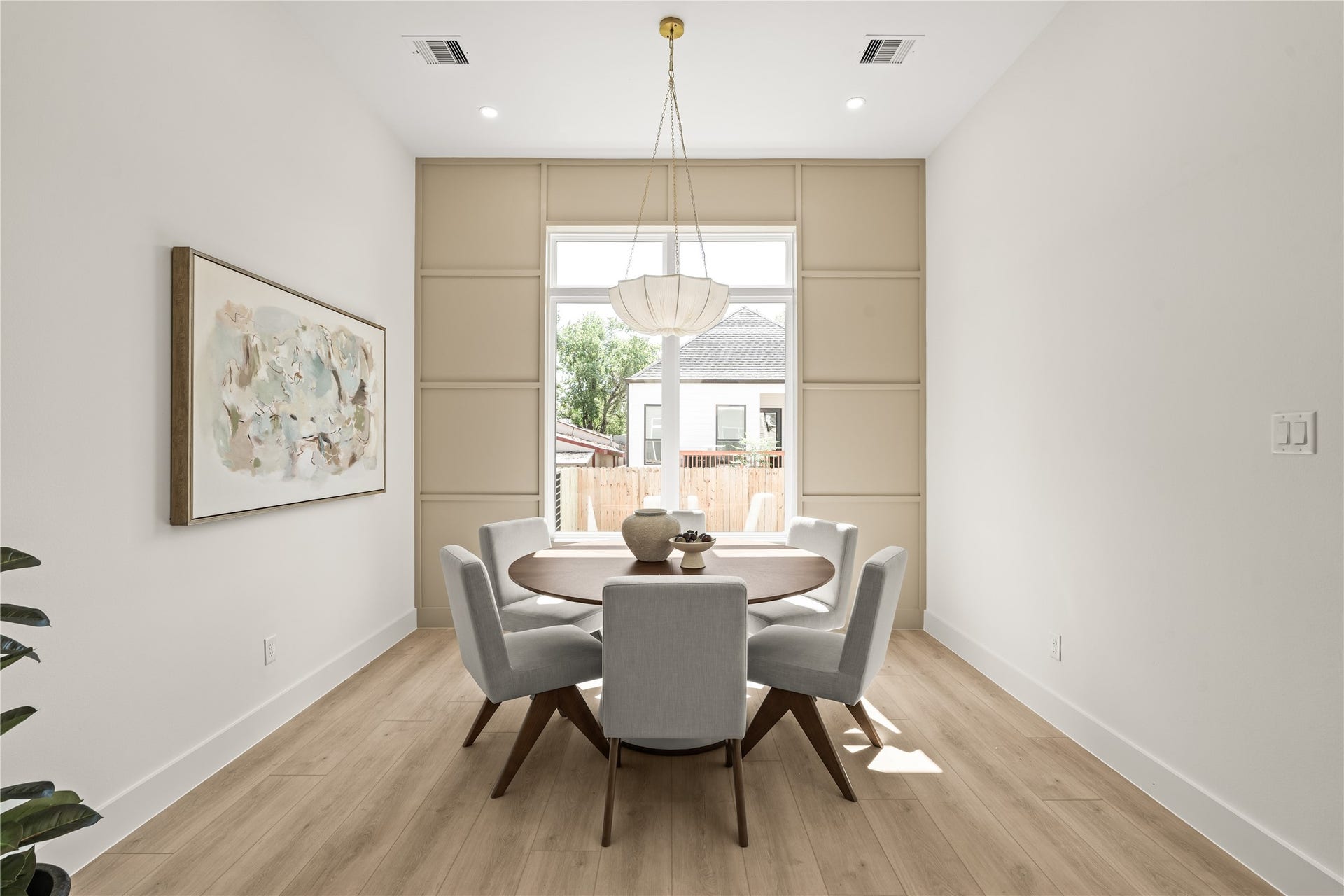 The dining wall in full. Wood paneling floor to ceiling, a cloud pendant over the round table, and enough room for eight.