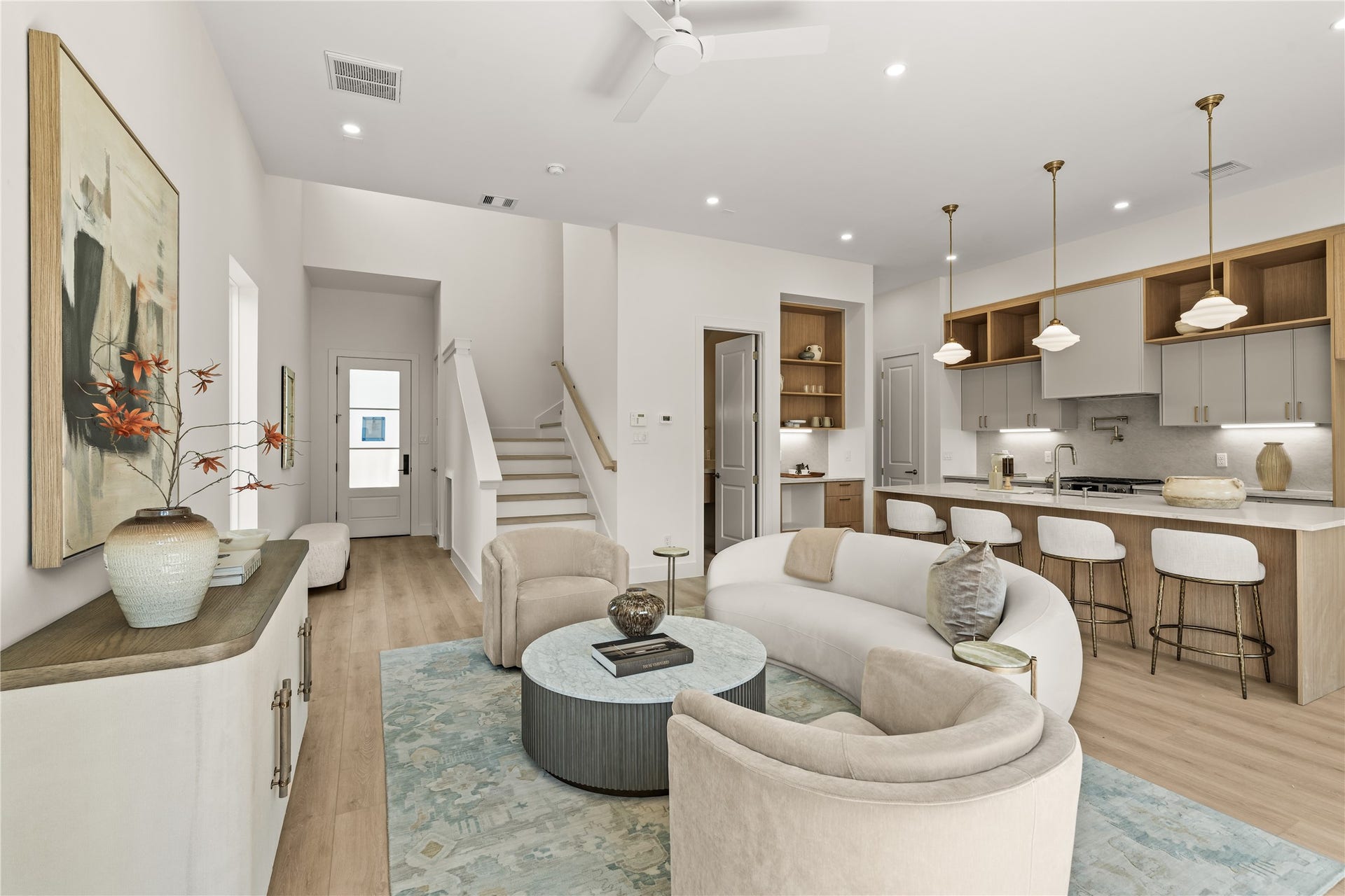 From the entry, the first floor opens all at once. Island and pendant lights straight ahead, dining to the left, living room to the right.
