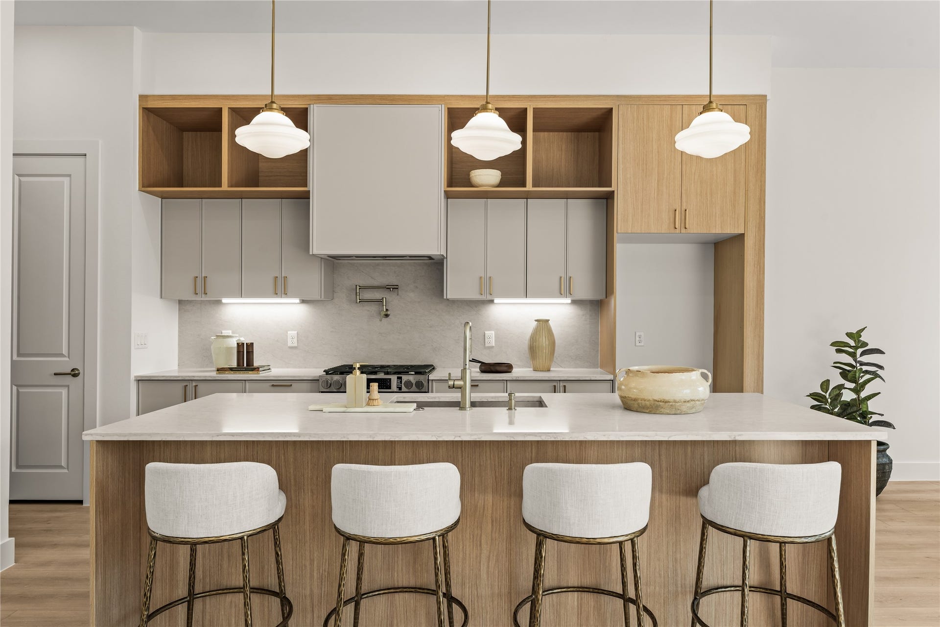 The cooking wall. Pot filler over the gas range, under-cabinet lighting, and open wood shelving above the quartz. The pantry door sits just to the left.