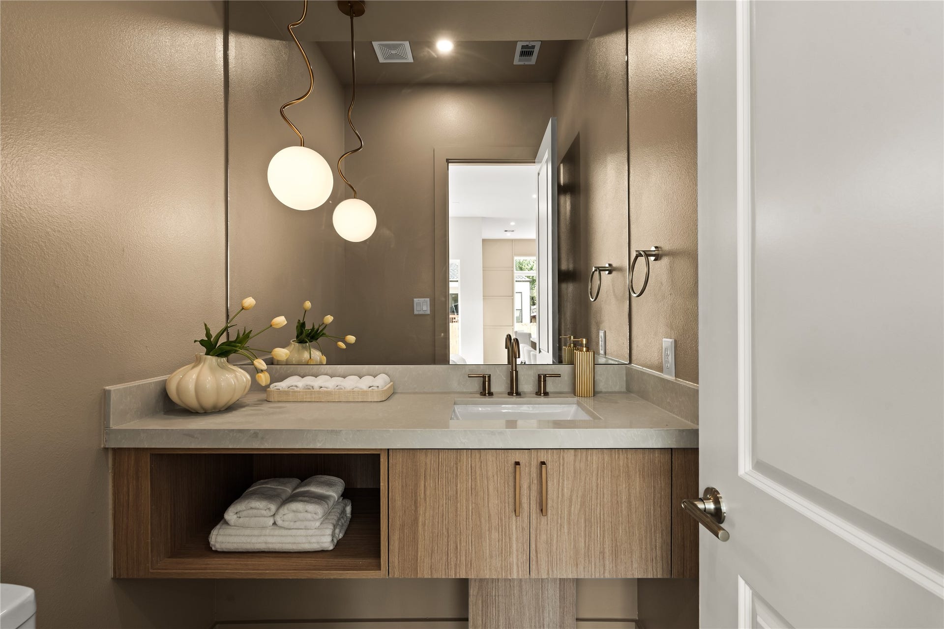 Half bath on the first floor. Floating wood vanity, quartz top, double pendant over the mirror, and walls that went dark on purpose.