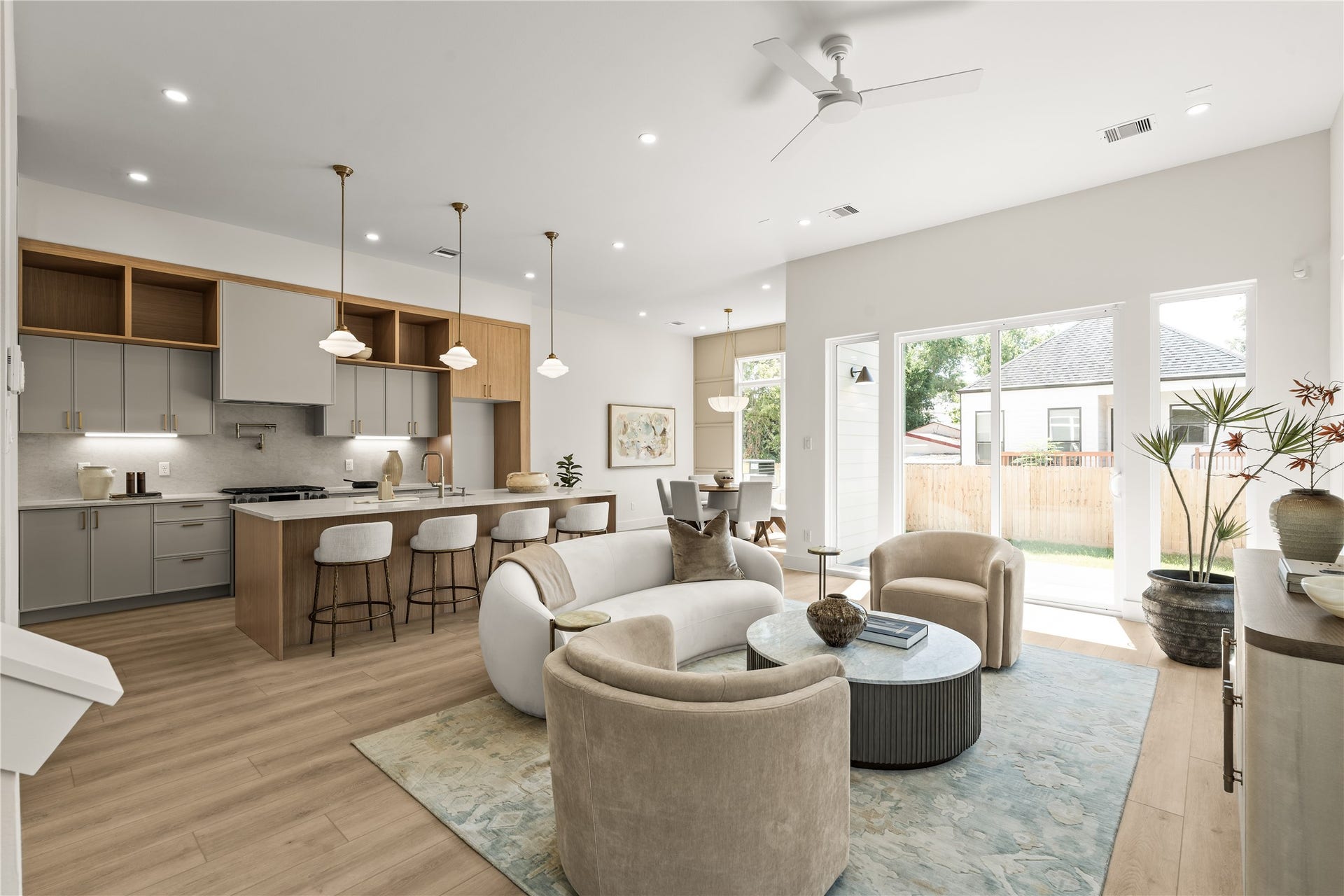 Kitchen, dining, and living in one open run across the back of the house. Sliders on the far wall go straight out to the covered patio and the yard.