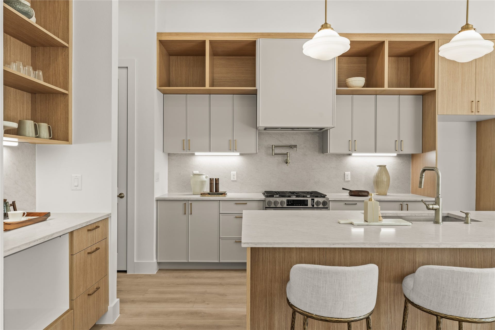 Open wood shelving meets the quartz counter where the coffee bar begins. Mugs, machine, and a run of drawers, all out of the main cooking lane.