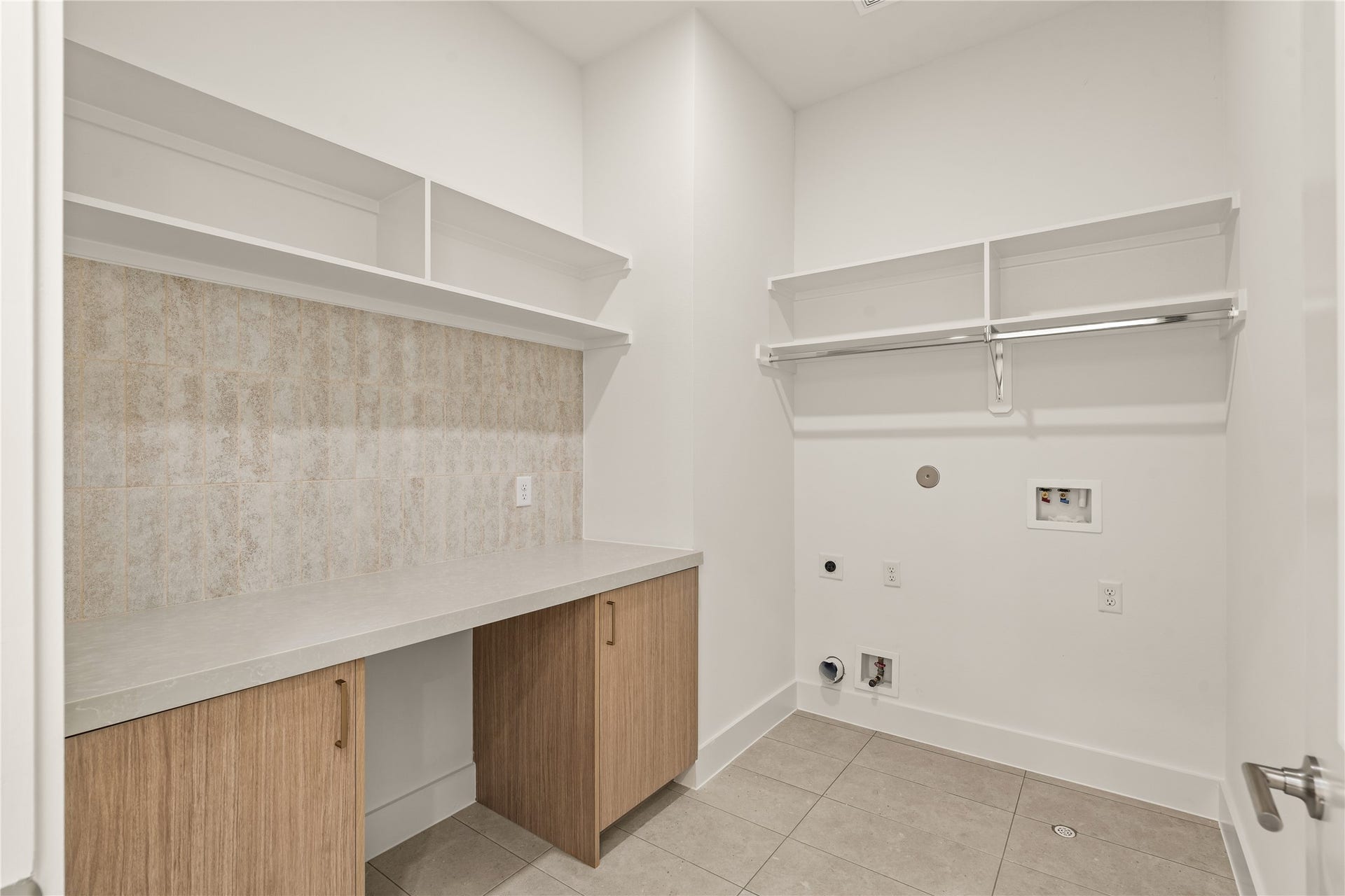 Utility room with a quartz folding counter, wood cabinets, and shelving over the washer and dryer. Tile floor, so spills do not matter.