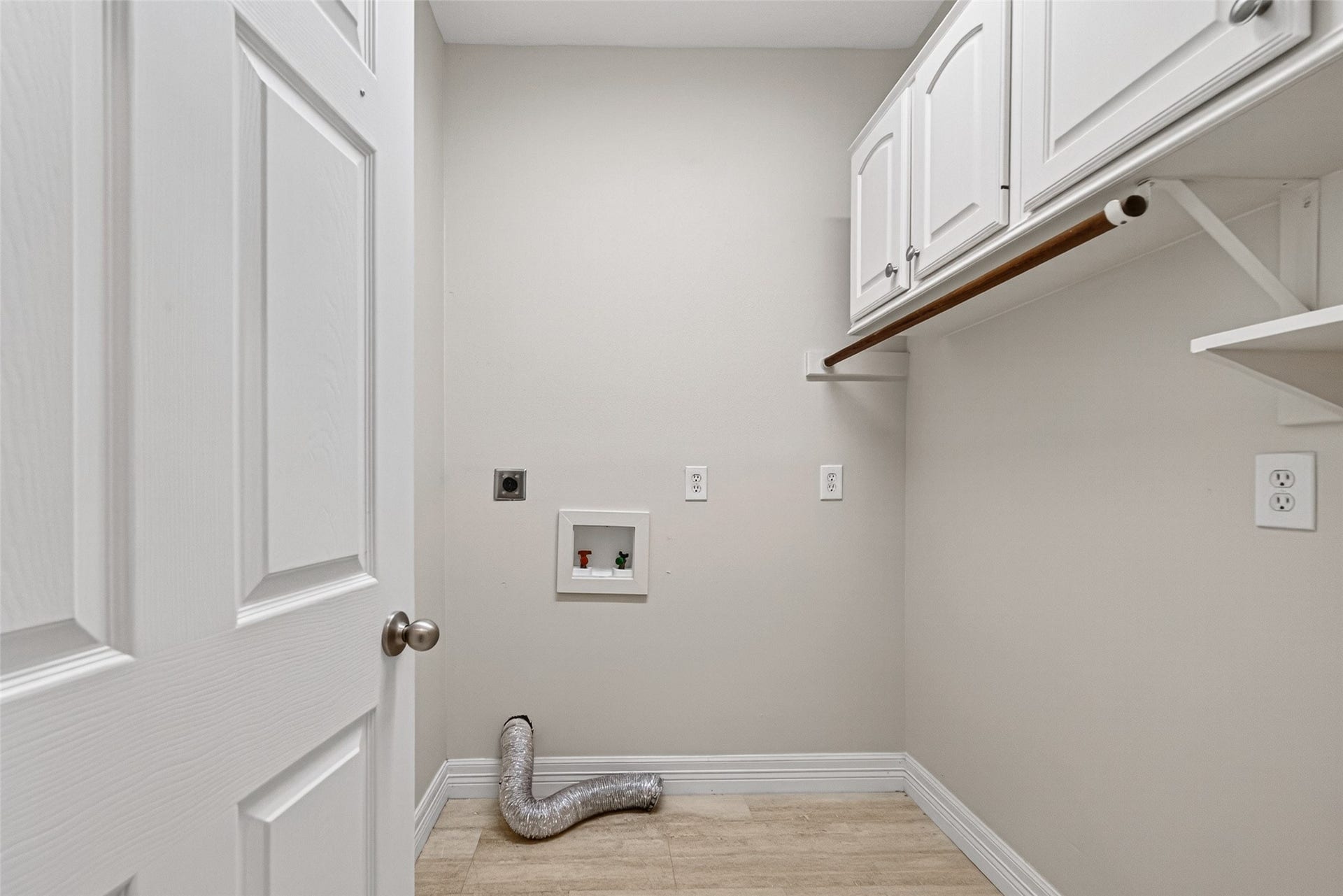 Laudry area with upper storage cabinets, and utility hookups, offering functionality and ample storage space.