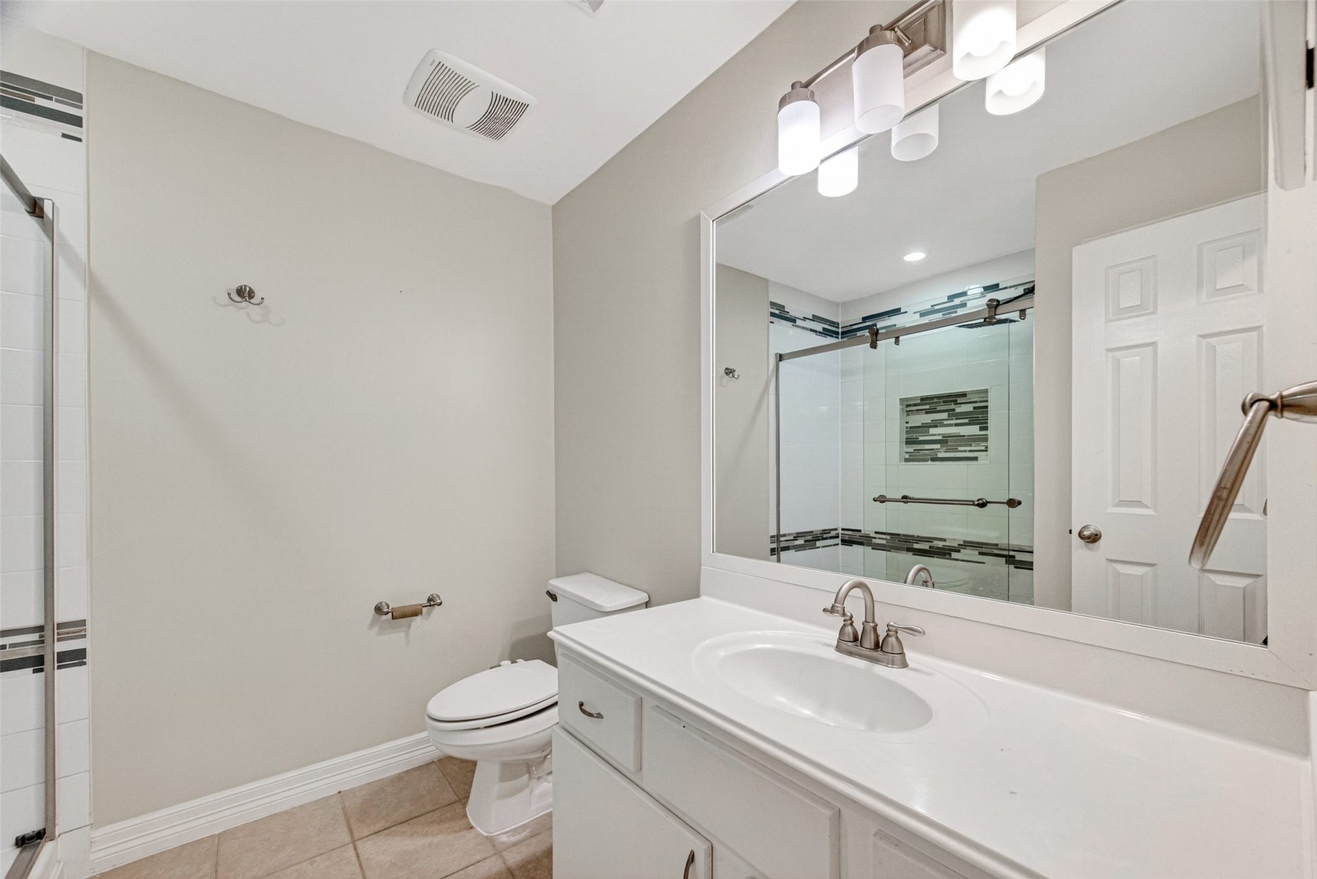 Upstairs Bathroom #3 boasts a sleek vanity with ample counter space, an elegant mirror, and a stylish walk-in shower adorned with contemporary tile accents.