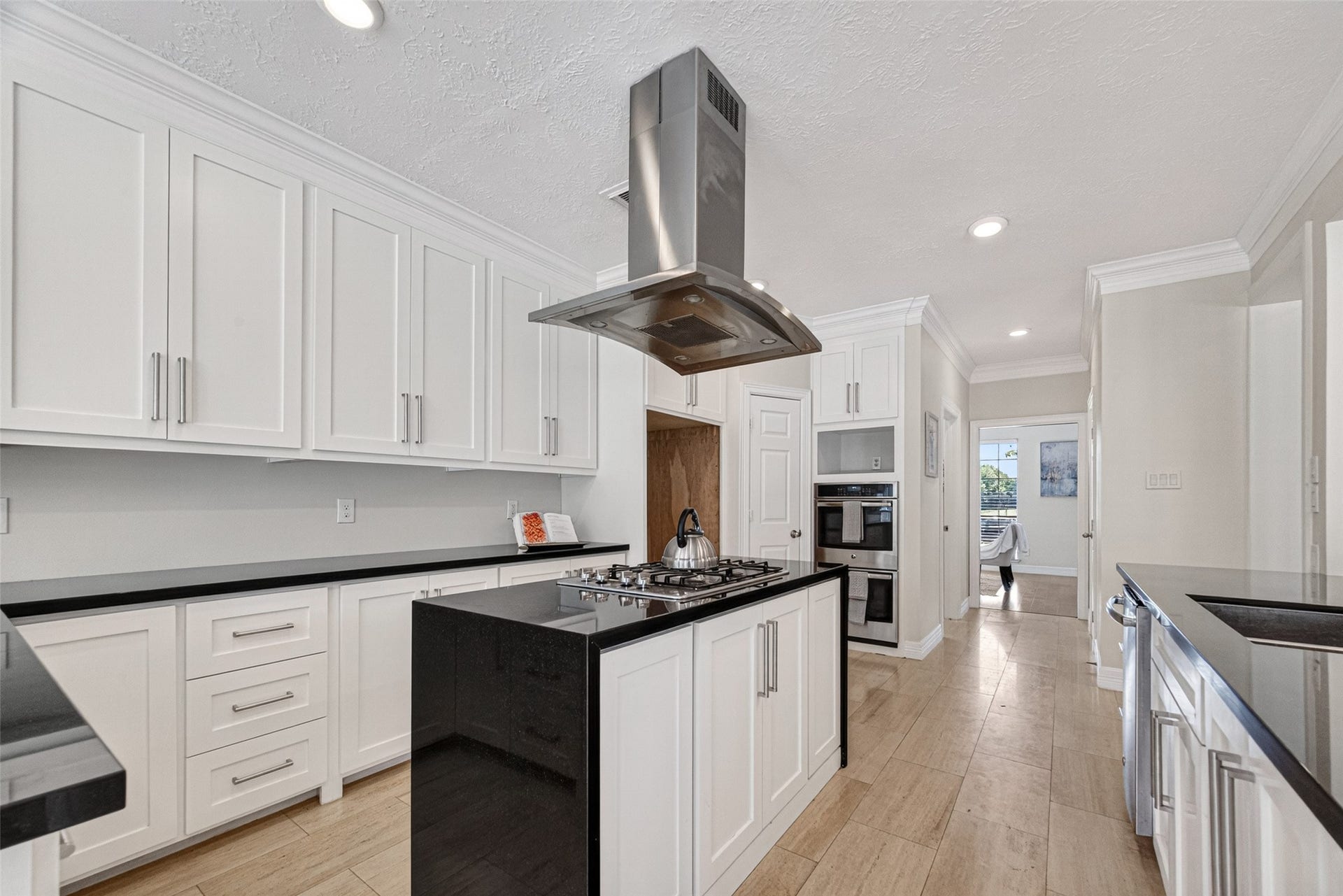 Sleek kitchen with modern appliances, featuring a central island with a cooktop and hood.