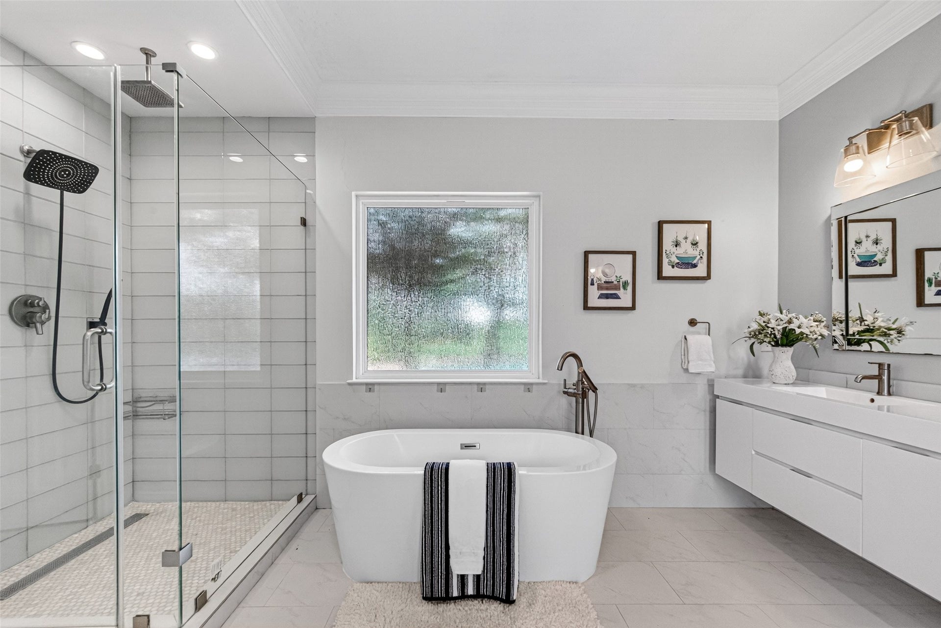 Luxurious bathroom featuring a freestanding tub, sleek glass-enclosed shower, and modern double vanity with elegant lighting.