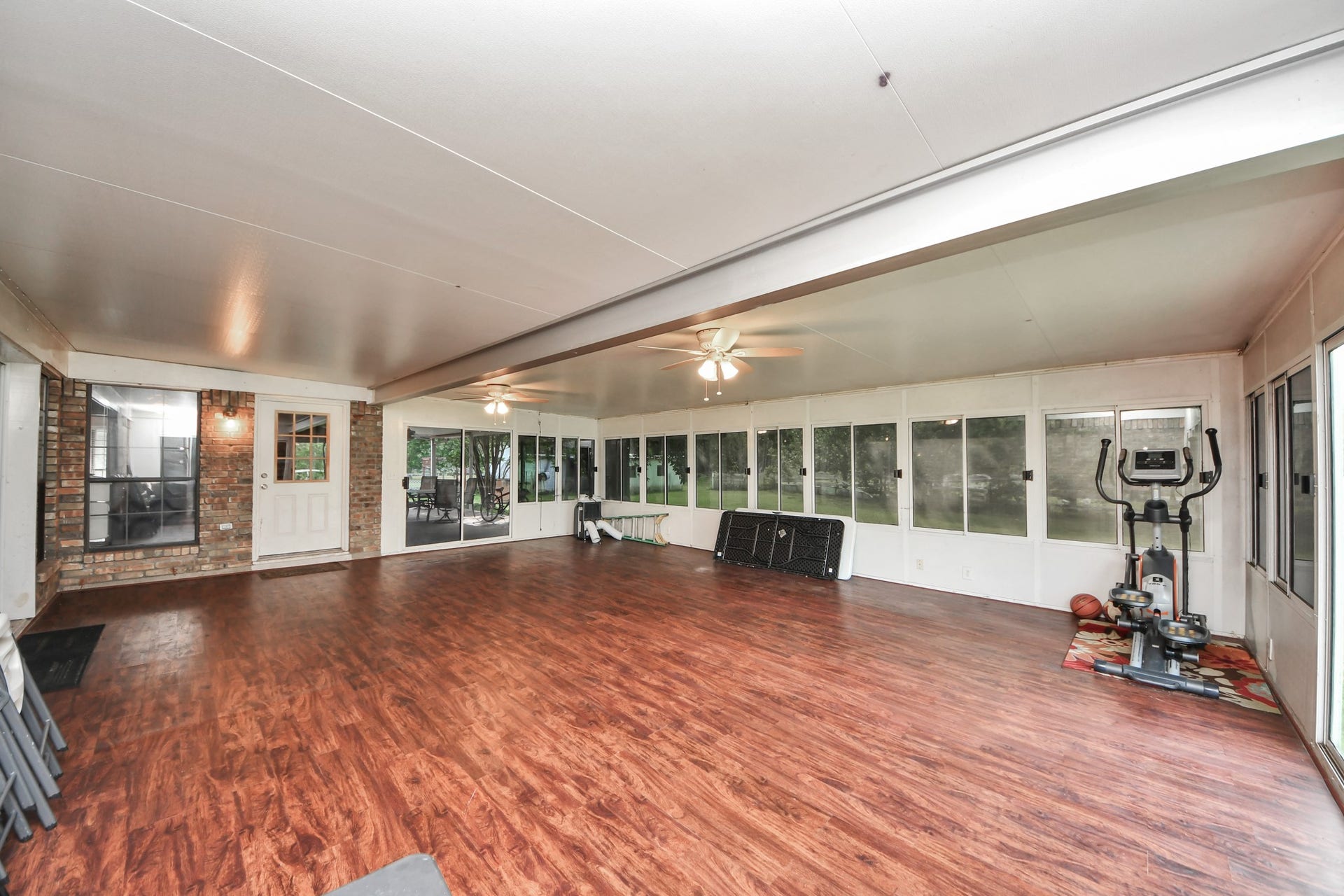 12746 Roy Road, Pearland, TX 77581 Spacious sunroom with large windows, wood flooring, ceiling fans, and a view of the backyard, perfect for relaxation or exercise.