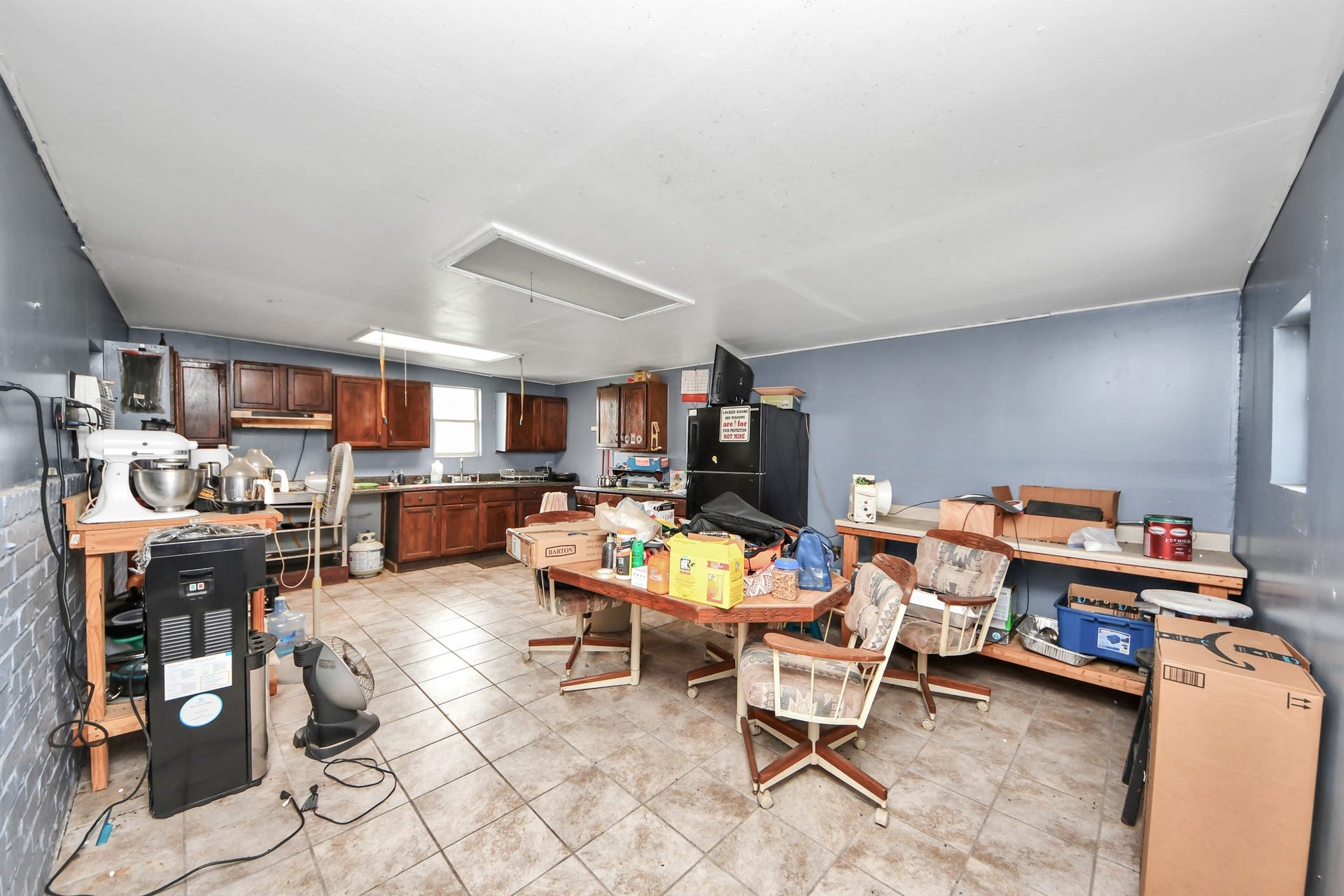 12746 Roy Road, Pearland, TX 77581 Spacious kitchen with tiled flooring and dark wood cabinets. Features ample counter space and natural light from a window. Some clutter is present, but offers potential for organization and personalization.