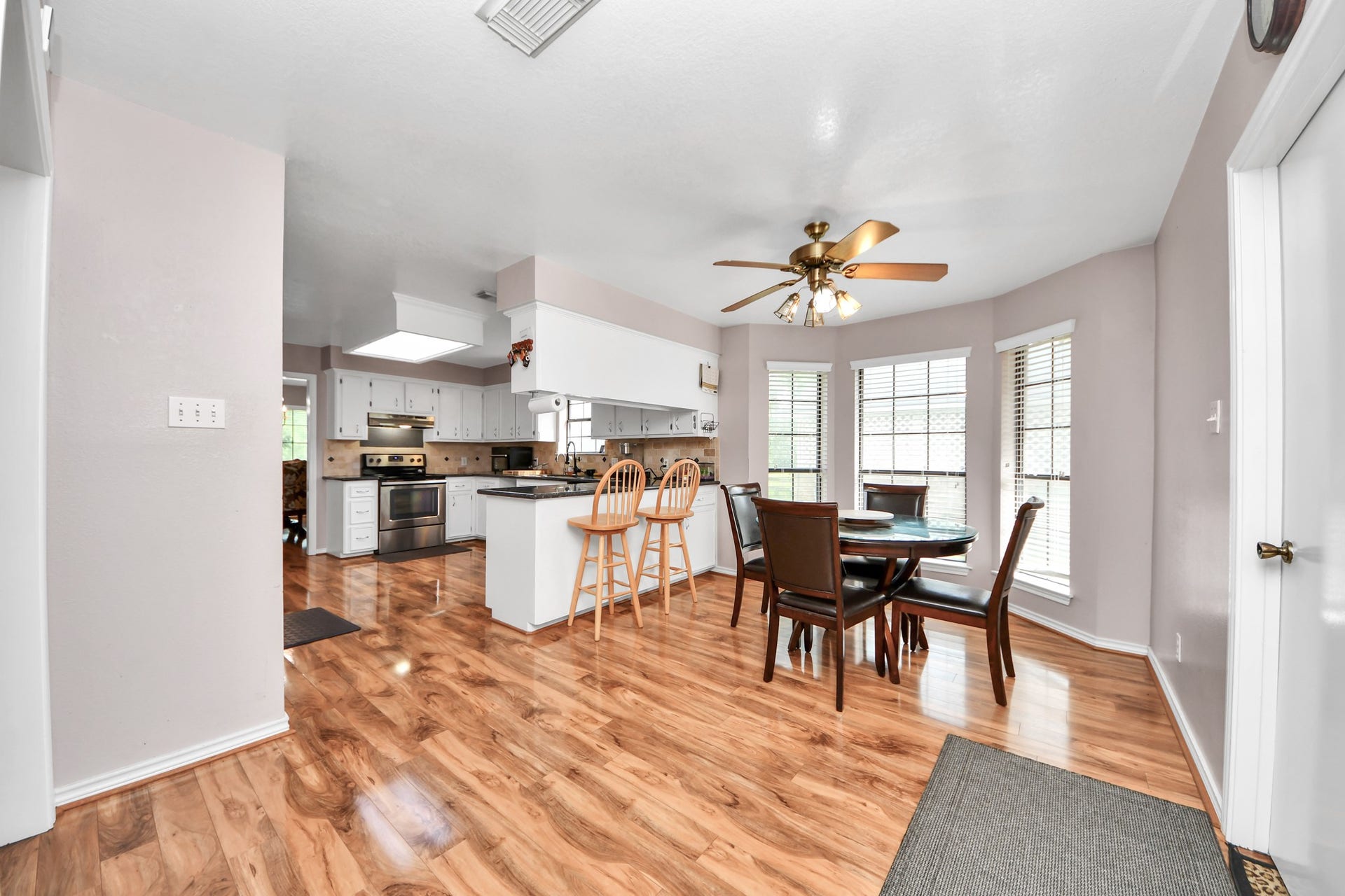 12746 Roy Road, Pearland, TX 77581 This inviting kitchen and dining area features warm wood flooring, ample natural light from large windows, a ceiling fan, and a modern stainless steel stove. The breakfast bar and dining table provide plenty of space for family gatherings.
