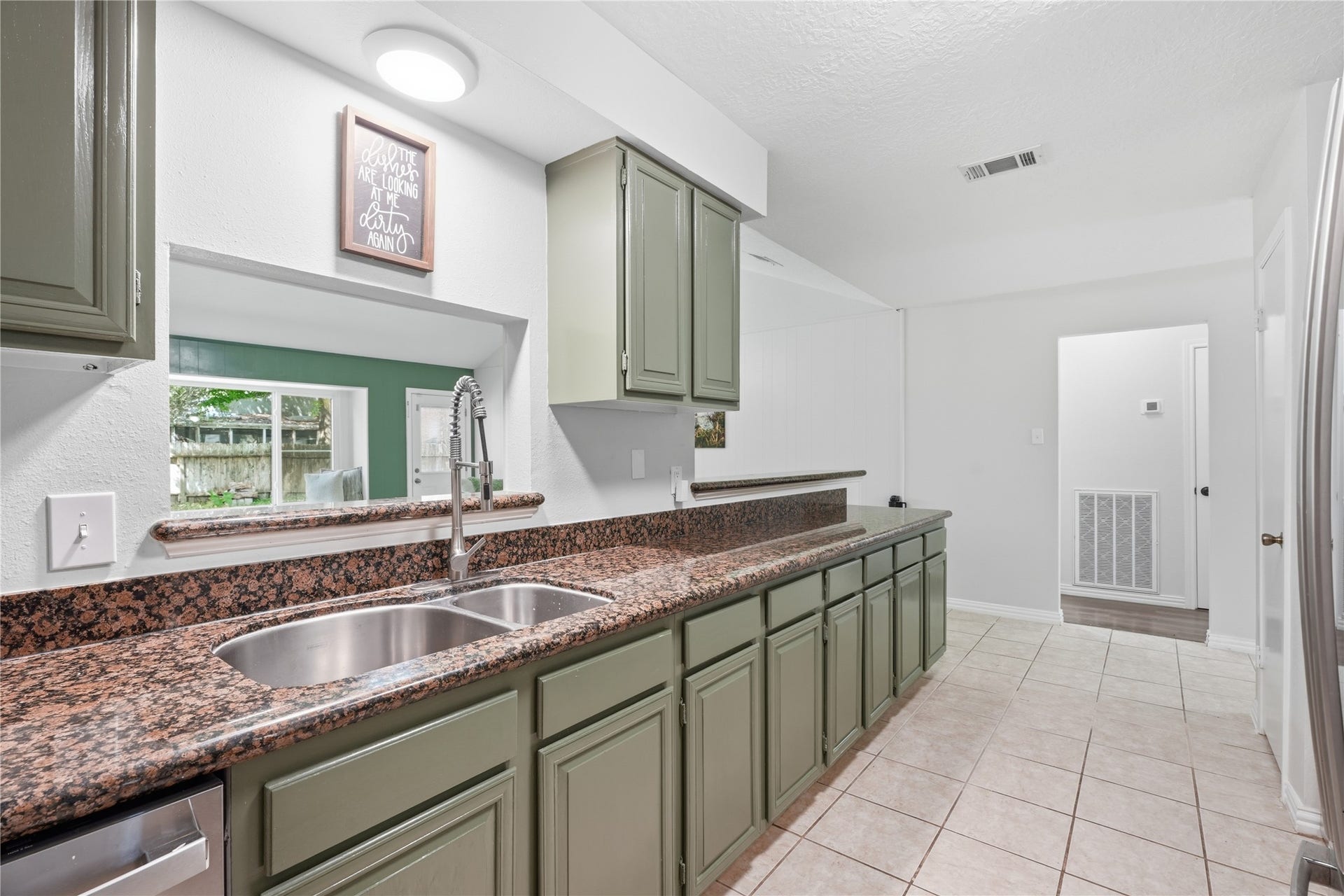 4850 Kentington Drive, Alvin, TX 77511 Kitchen featuring an oversized breakfast bar, double-basin sink with pull-down faucet, and an open pass-through overlooking the living room.