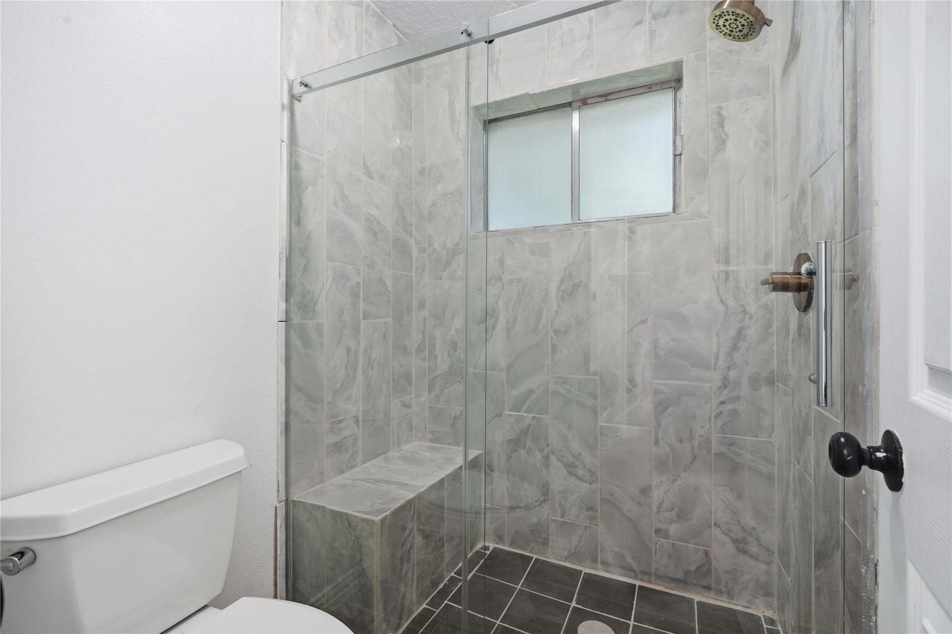 4850 Kentington Drive, Alvin, TX 77511 Updated primary bath with a beautifully tiled walk-in shower featuring a built-in bench, glass enclosure, and modern fixtures.