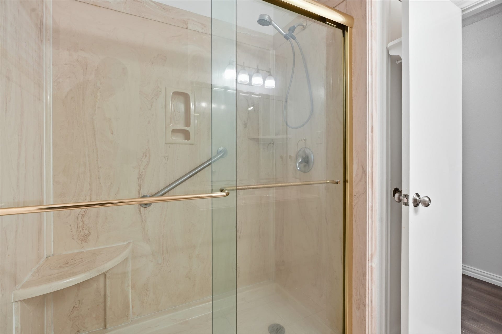 4850 Kentington Drive, Alvin, TX 77511 Secondary bathroom with a walk-in shower featuring sliding glass doors, built-in seating, and grab bars for added convenience.