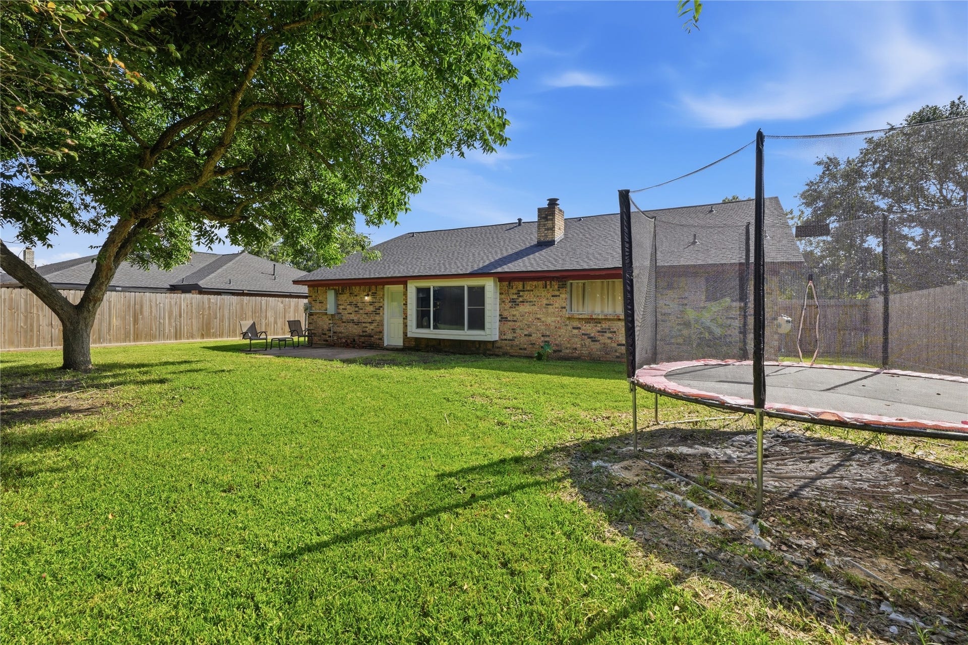 4850 Kentington Drive, Alvin, TX 77511 Expansive fenced backyard with mature shade trees, plenty of green space, and room for outdoor activities.