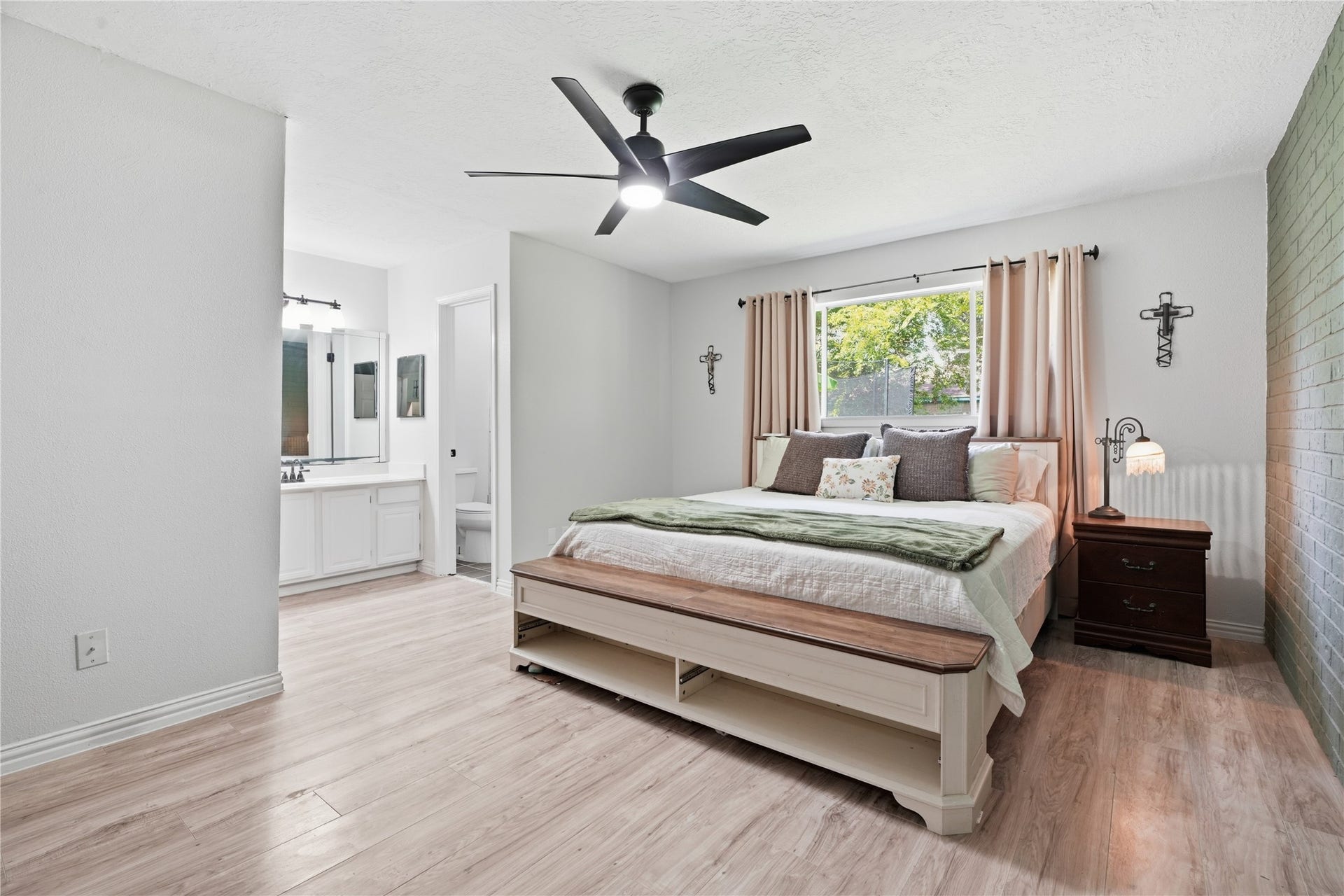 4850 Kentington Drive, Alvin, TX 77511 Expansive primary suite with ample space for a king-size bed, wood-look flooring, large window, and an ensuite bath with dual vanities.