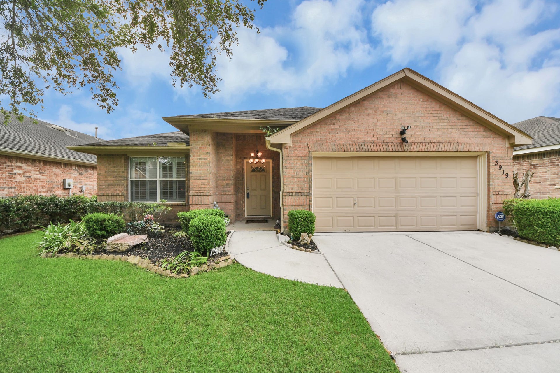 Welcome to 3919 W Auden Circle! This charming brick home in Sienna Steep Bank Village features a well-maintained front yard with lush greenery and a neat pathway leading to the entrance.
