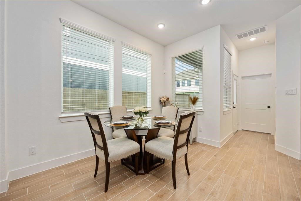 Virtually Staged - Bright and inviting dining area with large windows, stylish tile flooring, and a cozy four-seater table setting, perfect for intimate meals.