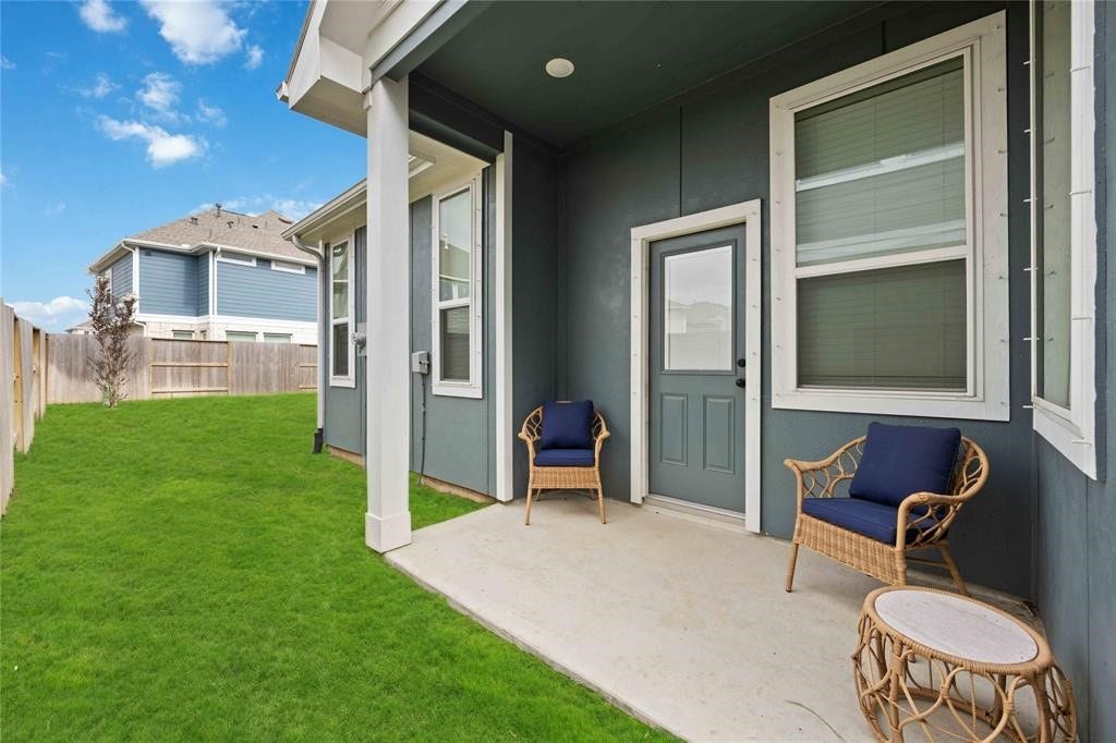 Virtually Staged - This photo showcases a cozy backyard patio with two wicker chairs and a small table, adjacent to a well-maintained lawn. The space is inviting and ideal for relaxation or outdoor gatherings.