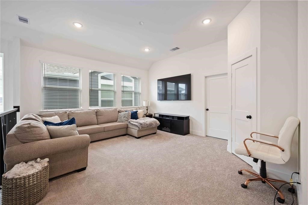 Virtually Staged - This spacious, bright living area features a cozy sectional sofa, a wall-mounted TV, and plush carpeting. Large windows offer ample natural light, while the neutral color palette creates a welcoming atmosphere.