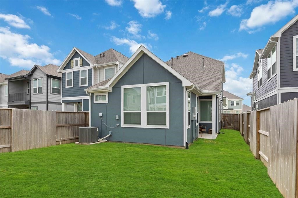 Virtually Staged - Charming two-story home with a well-maintained backyard, featuring a lush lawn and privacy fencing. The exterior is modern, with large windows providing ample natural light. Ideal for families seeking a cozy outdoor space.