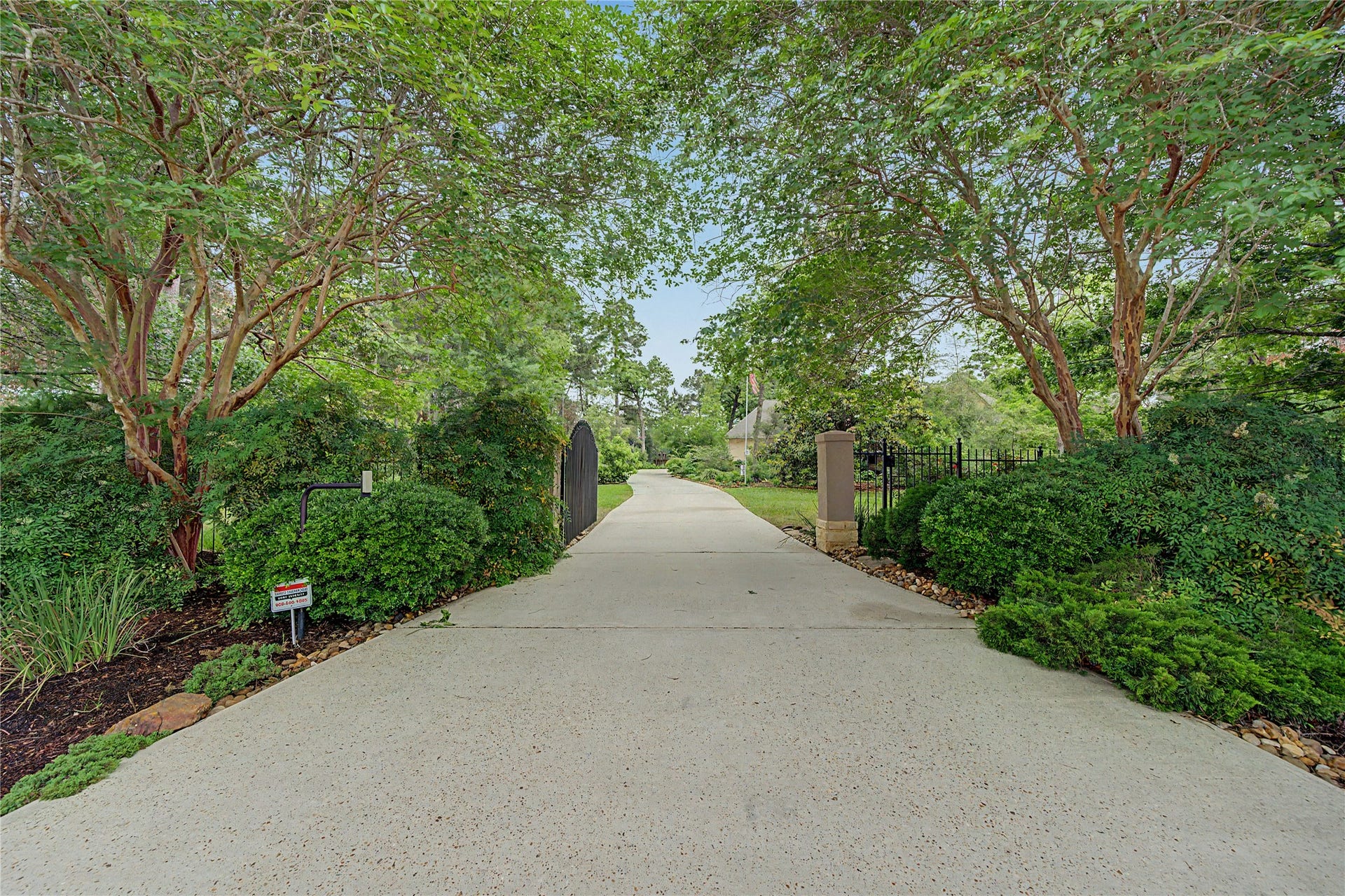 4423 Silver Jade Drive, Spring, TX 77386 Scenic driveway lined with lush greenery and mature trees, leading to a gated entrance. Perfect for privacy and a serene, welcoming atmosphere.