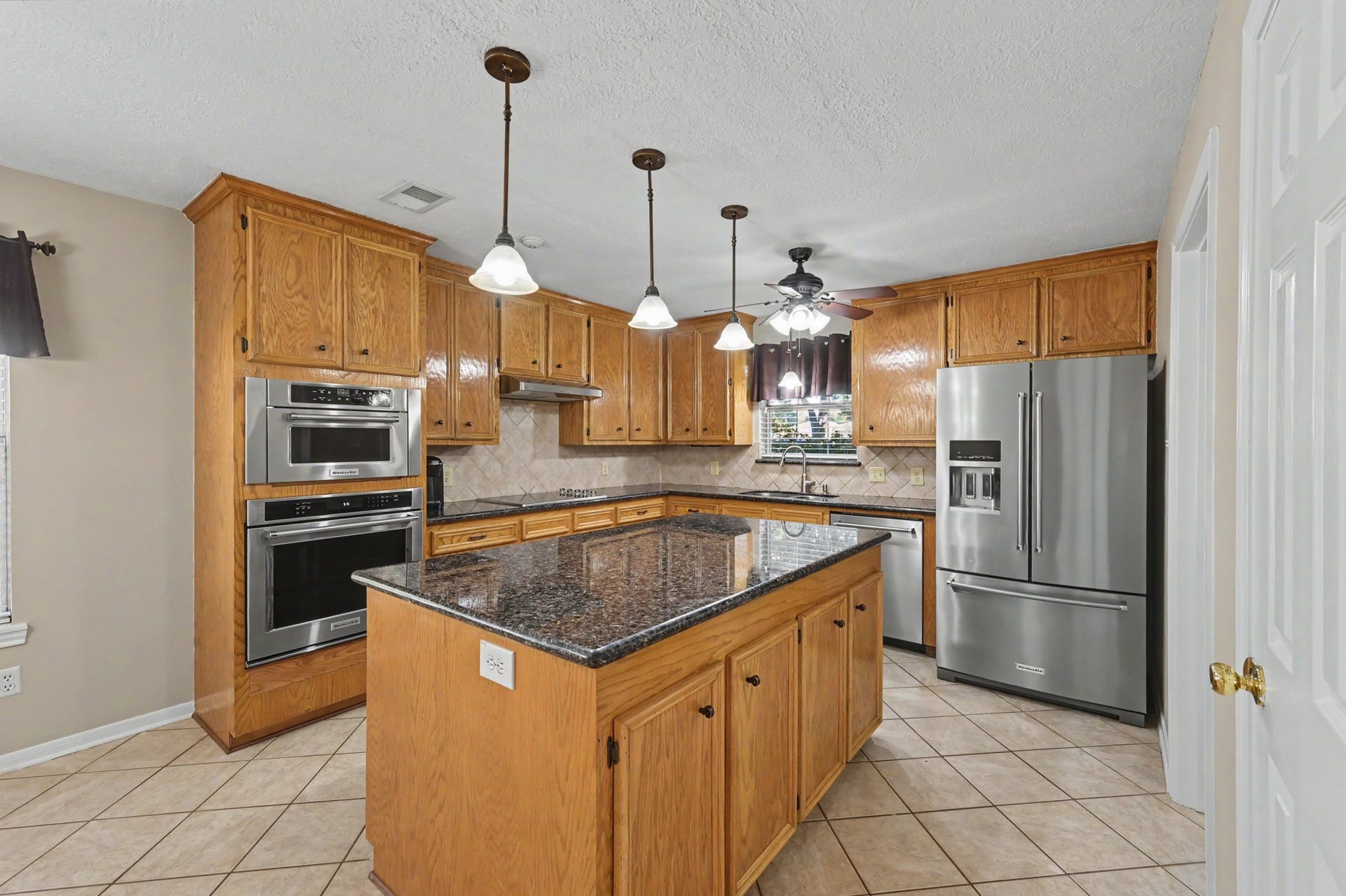 419 Dover Lane, Spring, TX 77373 Another view of the kitchen boasting tons of storage, beautiful granite countertops, a central island, and Kitchenaid stainless steel appliances.