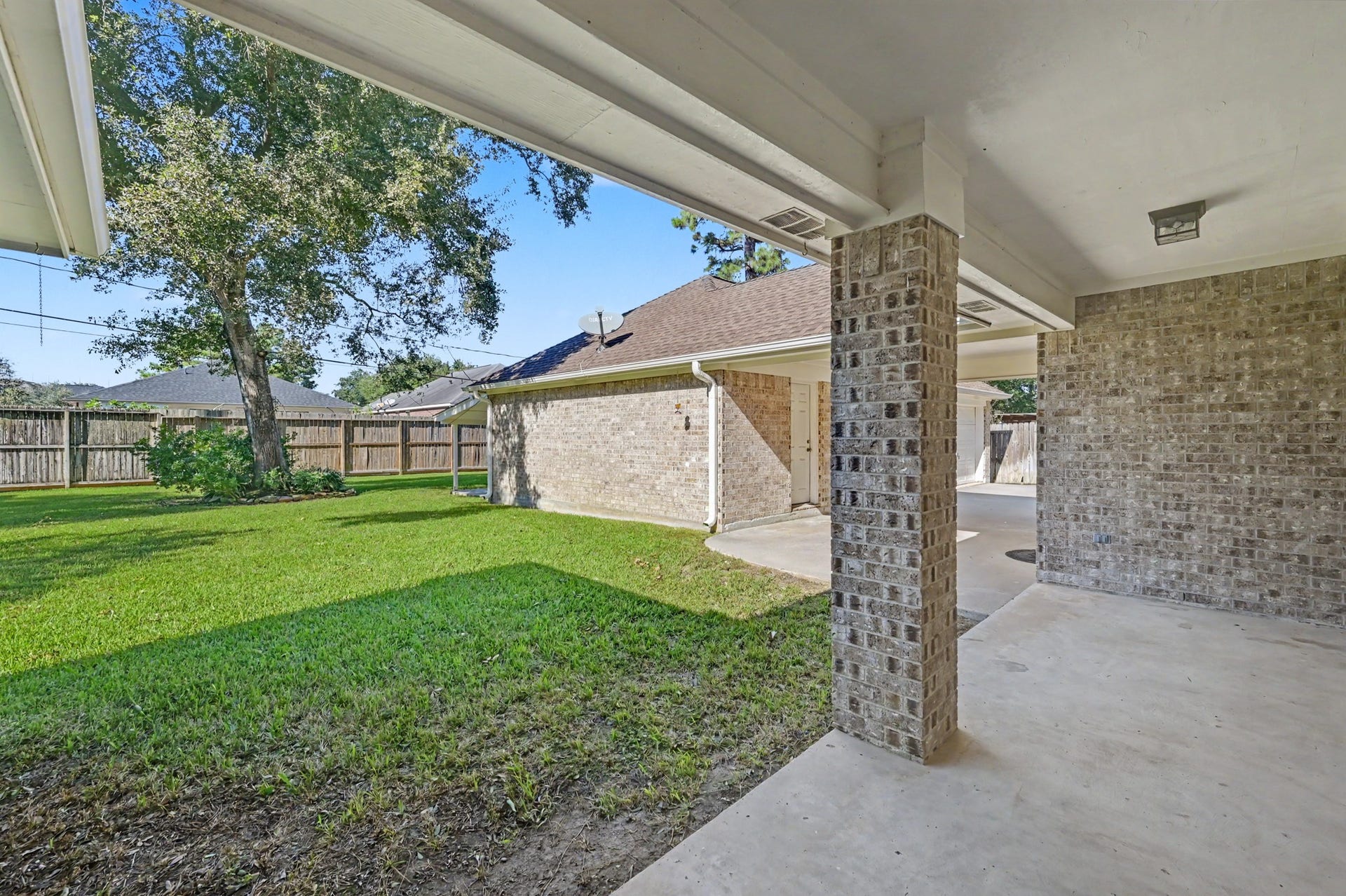 419 Dover Lane, Spring, TX 77373 Charming covered patio overlooking a spacious backyard with lush green grass and mature trees, perfect for outdoor relaxation and entertaining.