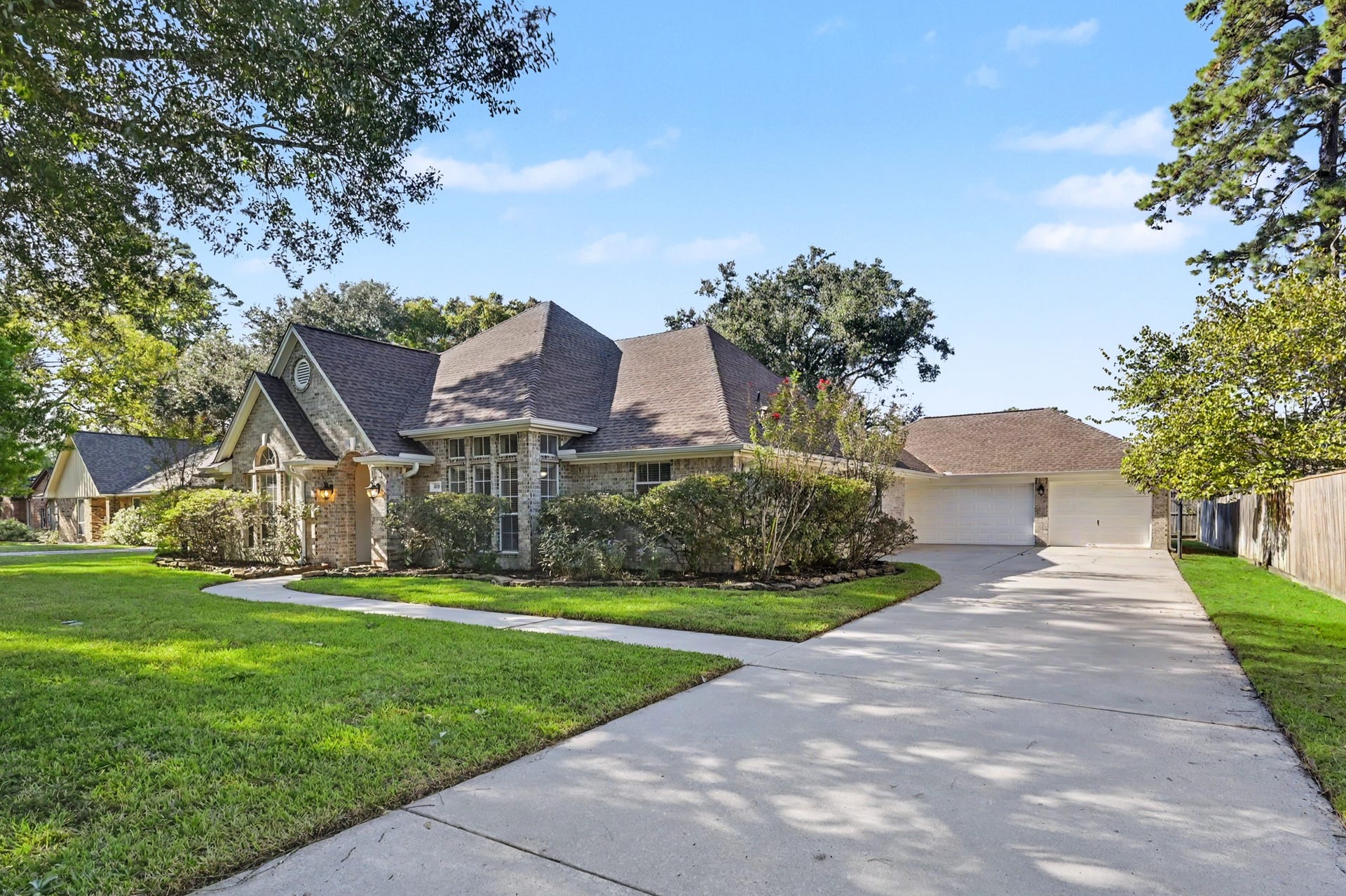 419 Dover Lane, Spring, TX 77373 Charming home with a classic brick exterior, nestled on a spacious lot with lush greenery and mature trees. The long driveway leads to a large 3-car garage, offering ample parking space.
