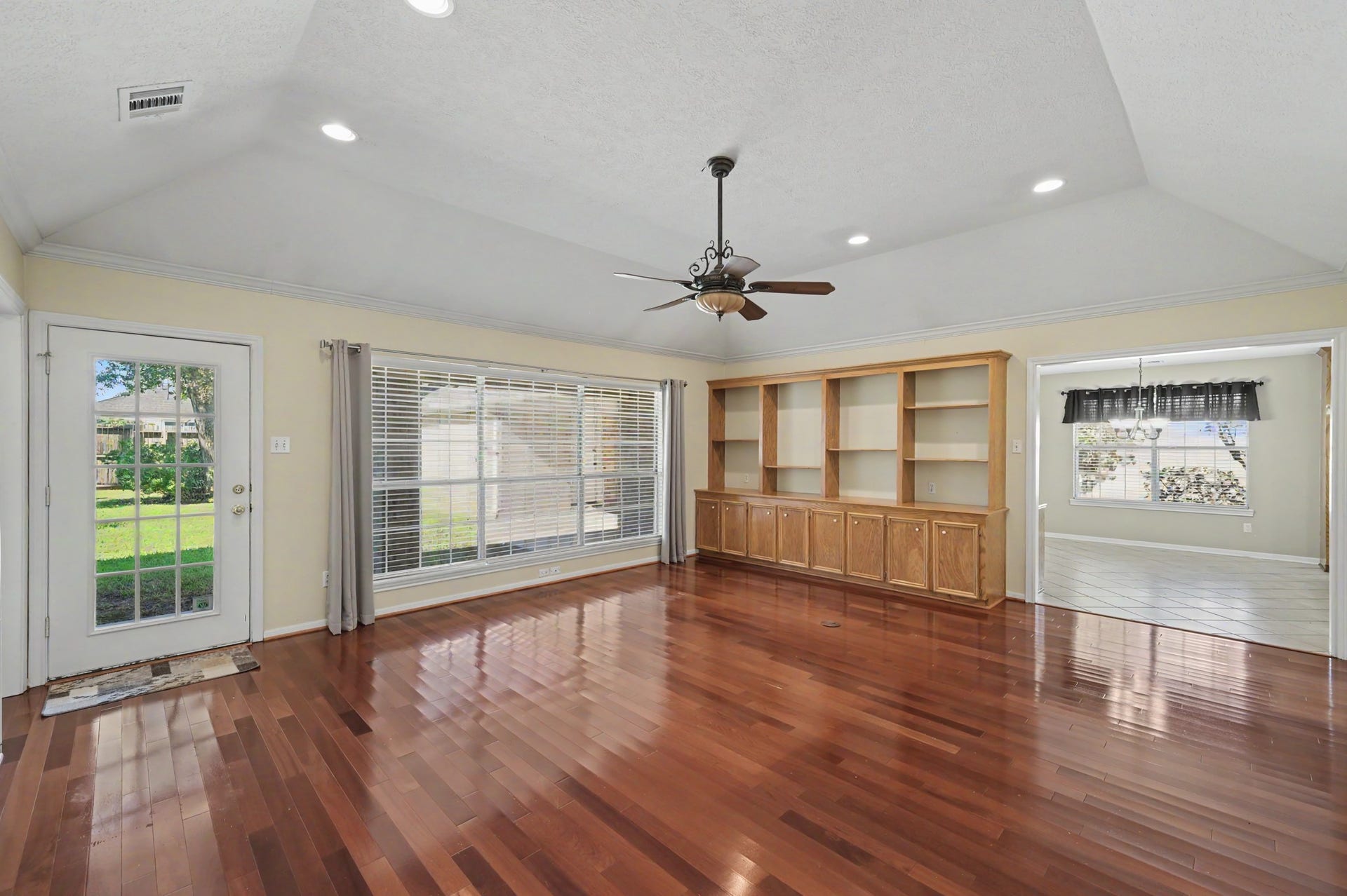 419 Dover Lane, Spring, TX 77373 Spacious living area with rich hardwood floors, large windows for natural light, and beautiful built-in shelving, seamlessly connecting to a bright kitchen space with plenty of room for casual dining.