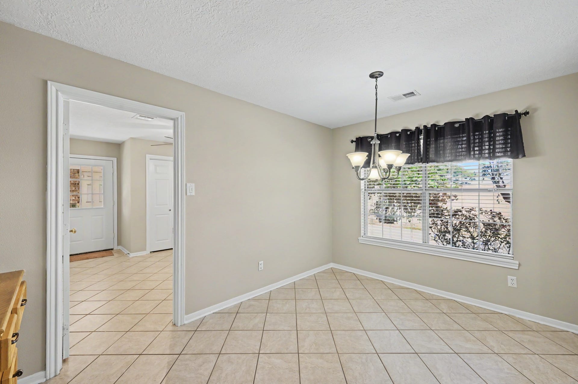419 Dover Lane, Spring, TX 77373 Bright dining area with tiled floors, and a large window offering natural light and garden views. Doorway leads into a large office space with tons of storage and a laundry closet, along with a backyard exit.