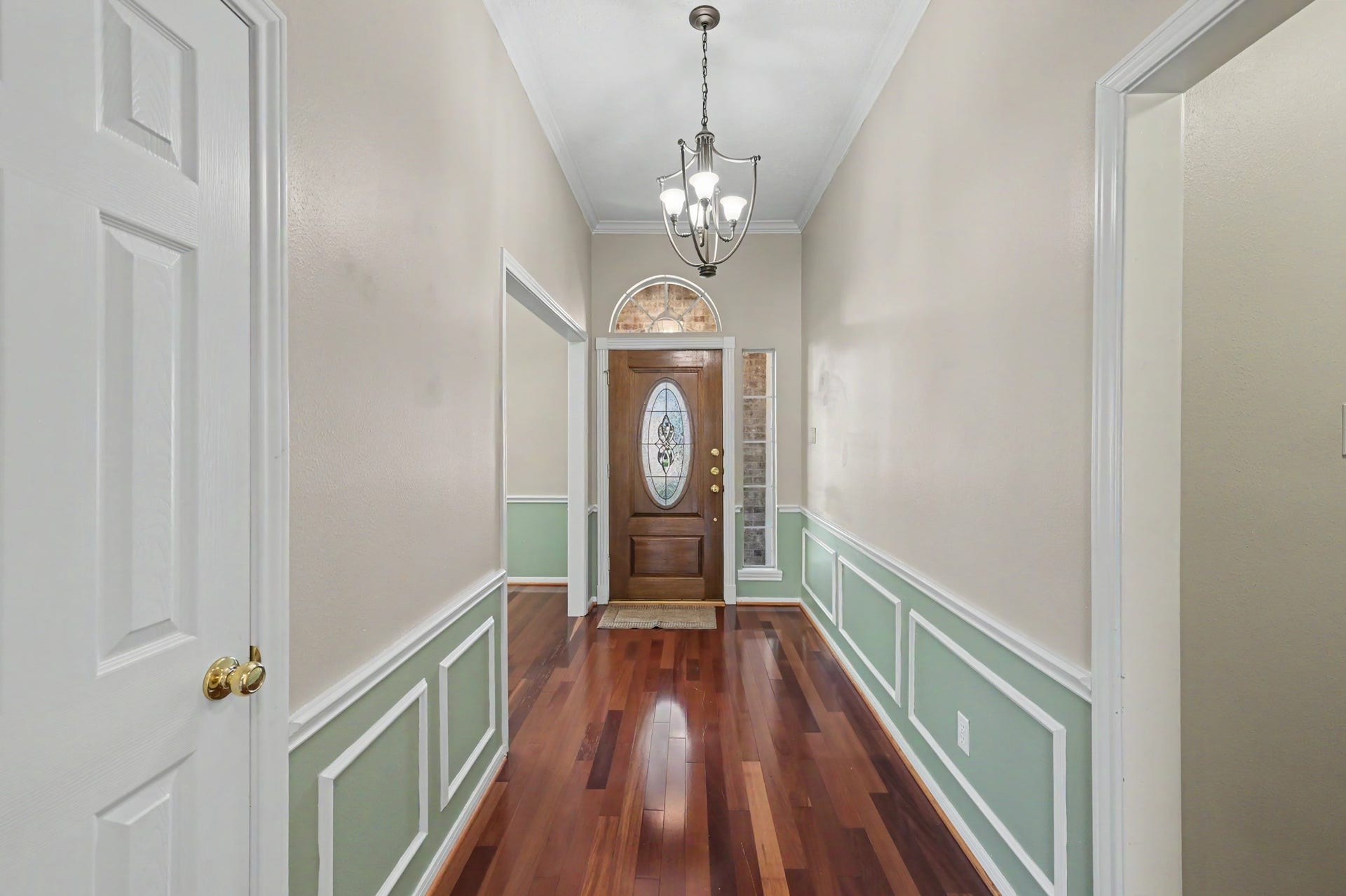 419 Dover Lane, Spring, TX 77373 Elegant entryway featuring rich hardwood floors, wainscoting, and a decorative chandelier leading to a beautiful wooden front door with glass insets.