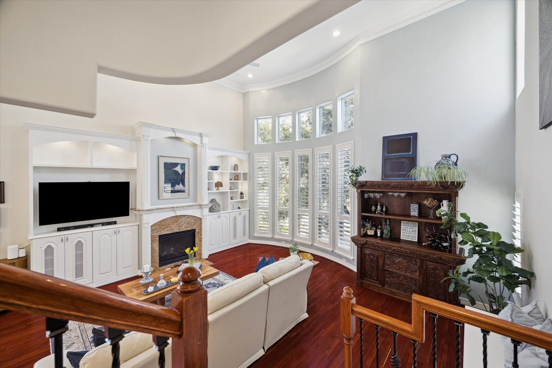 5717 Val Verde Street, #C, Houston, TX 77057 The semi bay windows with plantation shutters, built-in entertainment center, a fireplace, elegant shelving, and natural light, adds functionality with a warm ambiance.