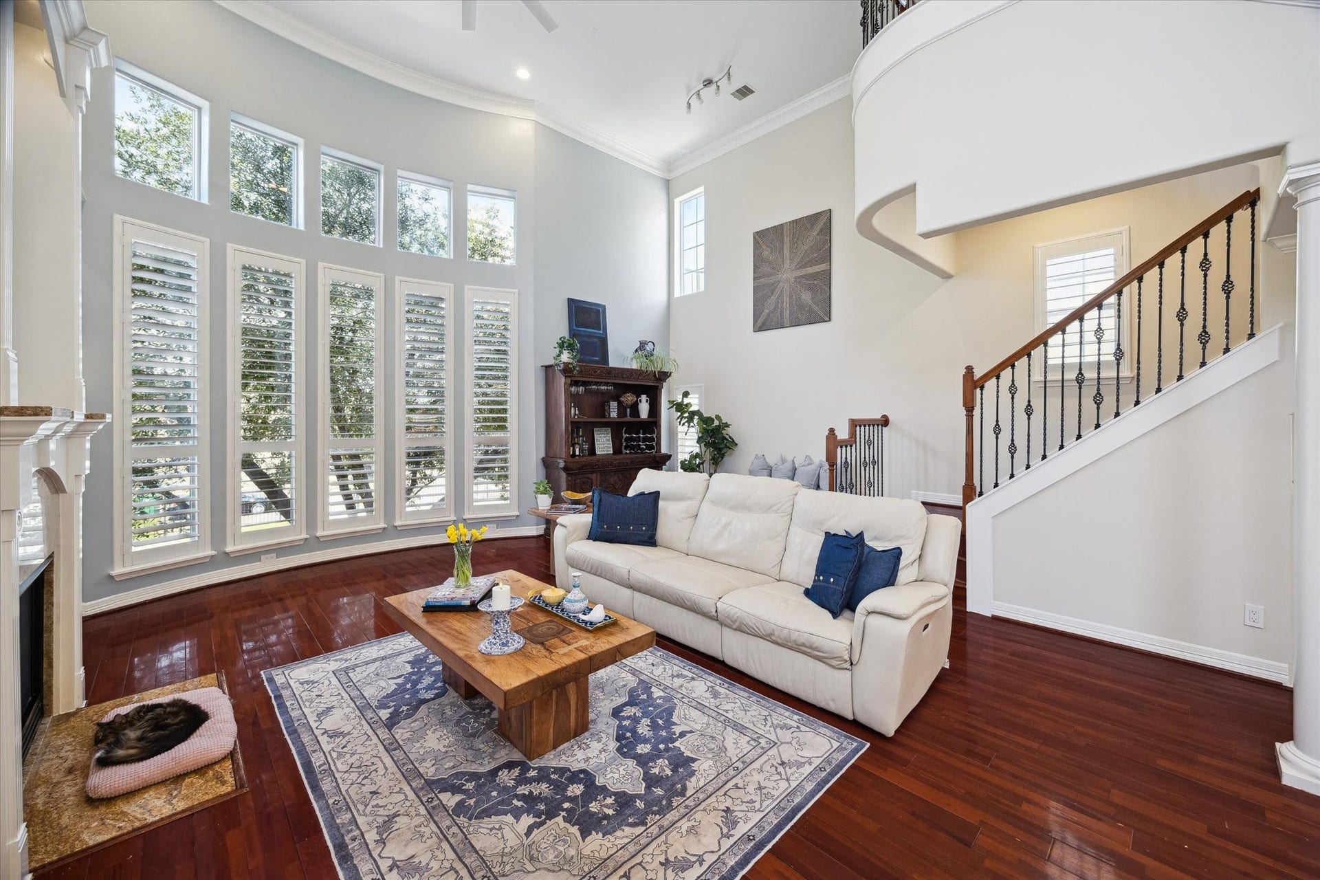 5717 Val Verde Street, #C, Houston, TX 77057 This inviting living room features high ceilings, large windows with Plantation blinds, and rich wooden floors. The elegant staircase adds a touch of sophistication.