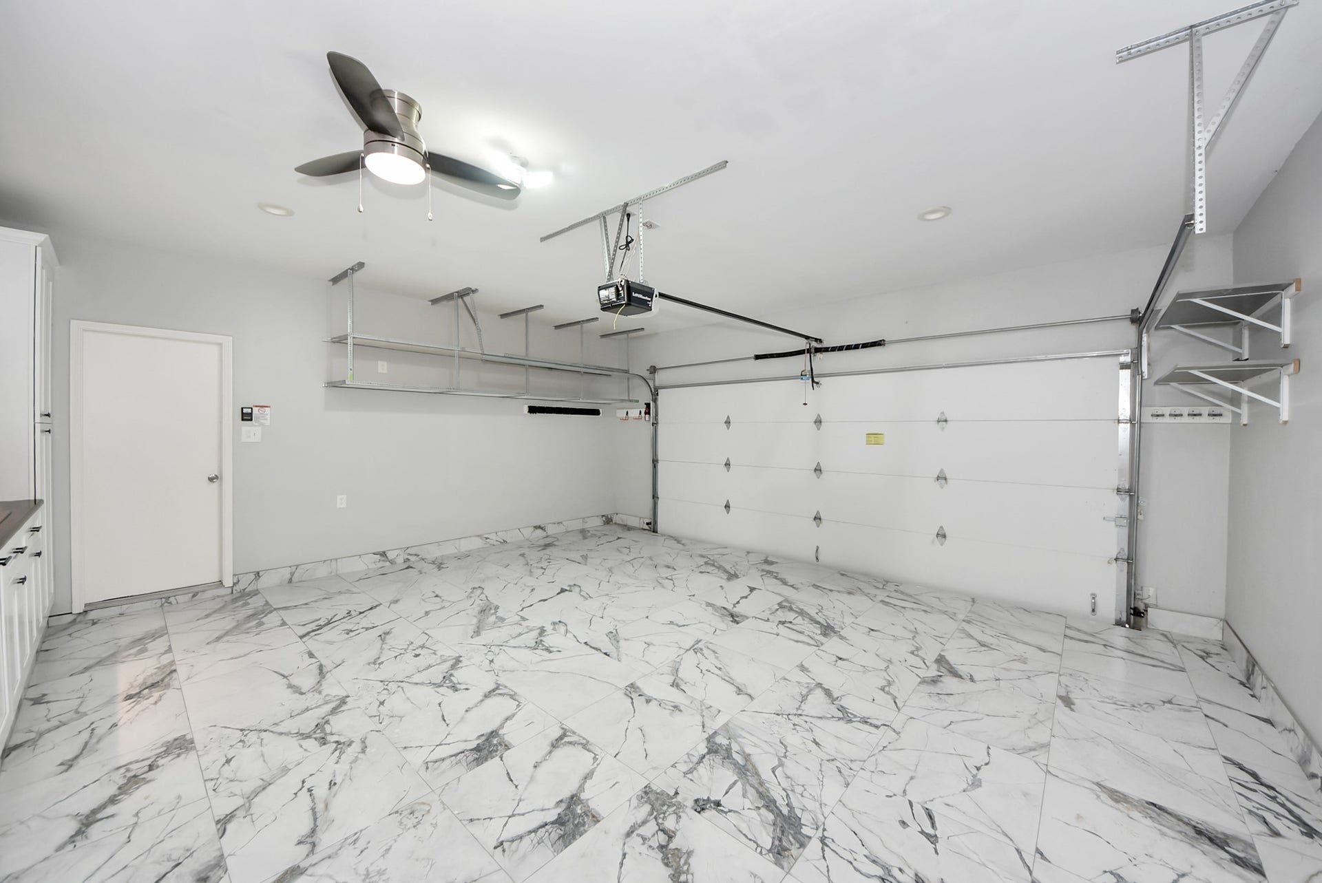 This garage offers far more than a place to park, featuring finished flooring and upper storage racks.
