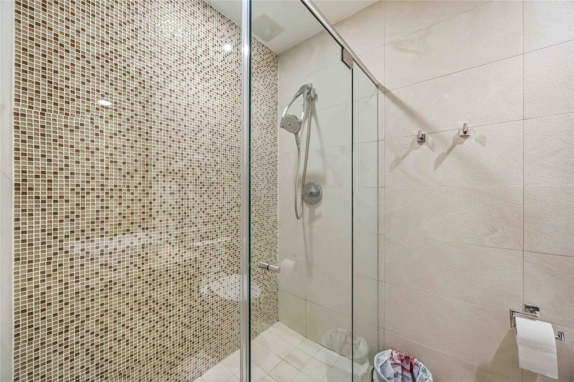 7610 Guinevere Drive, Sugar Land, TX 77479 Walk-in shower with seamless glass, chrome showerhead, and mosaic tile accent wall.