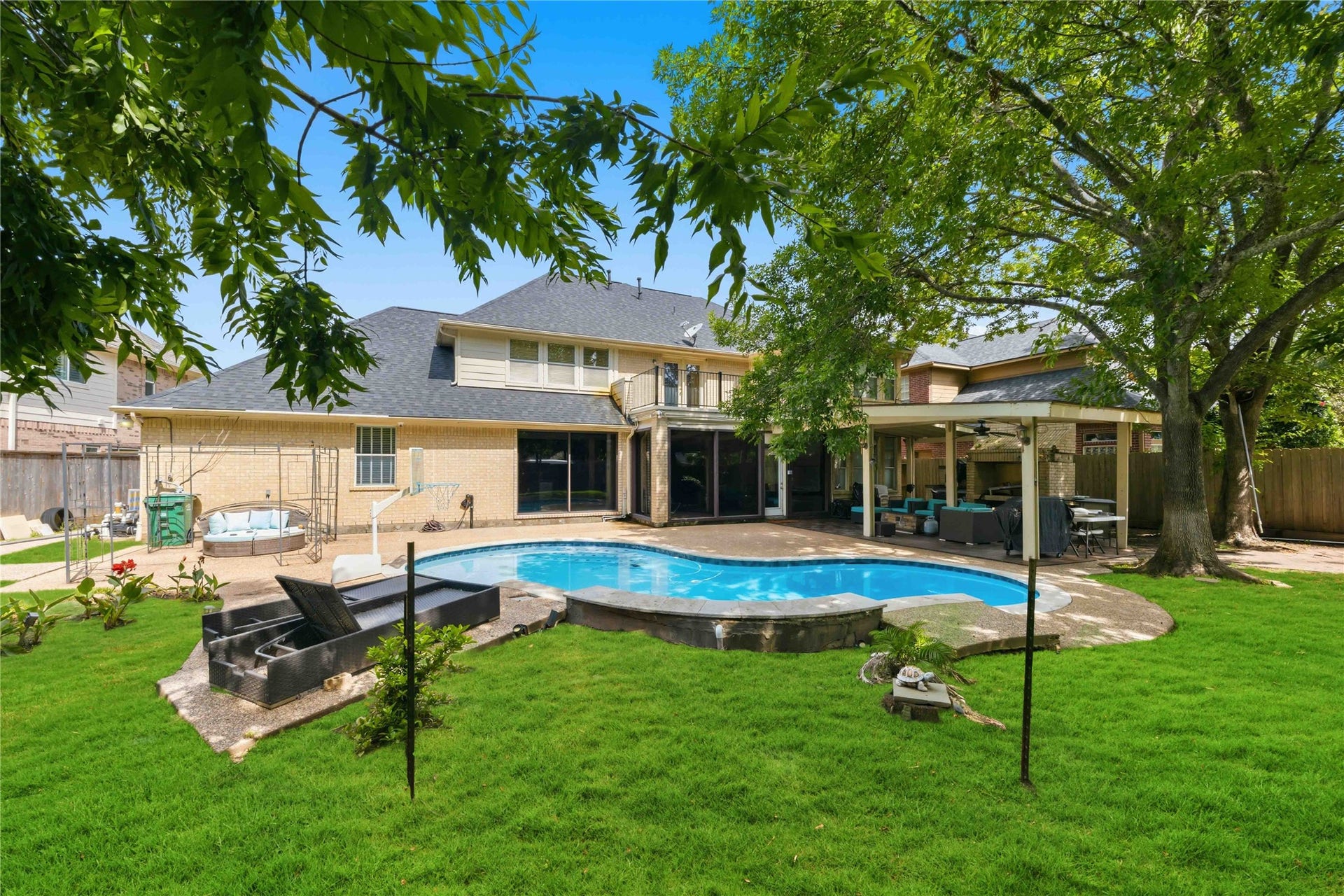 7610 Guinevere Drive, Sugar Land, TX 77479 The impressive rear elevation showcases the multi-gabled roofline, an upper balcony, a covered patio wing, and an expansive pool deck.