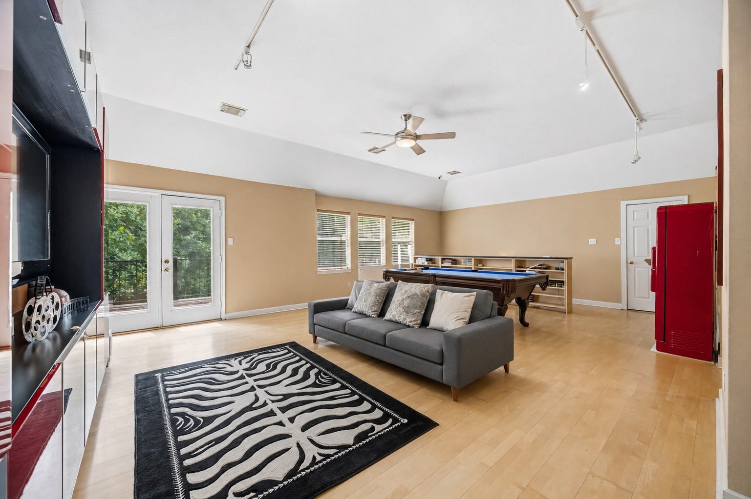 7610 Guinevere Drive, Sugar Land, TX 77479 The expansive upper-level game room boasts vaulted ceilings, track lighting, light wood floors, and double glass doors that open to a private balcony.