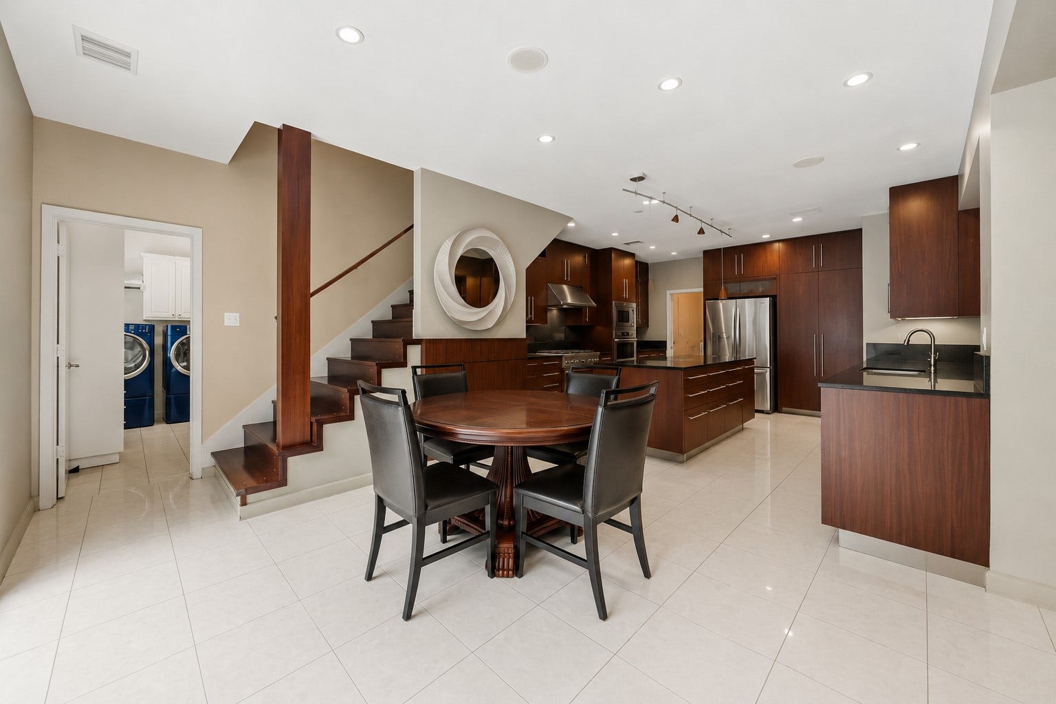 7610 Guinevere Drive, Sugar Land, TX 77479 An open-concept dining space flows into the kitchen area, featuring light tile flooring and a view of a wooden staircase built into the wall.