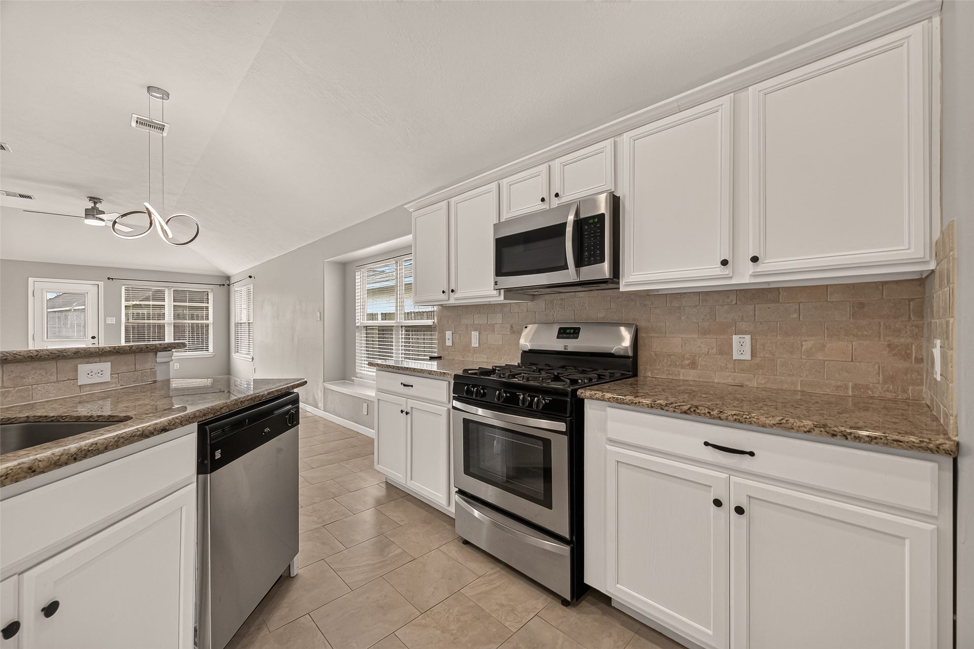Bright and spacious kitchen with modern stainless steel appliances, elegant granite countertops, and ample white cabinetryideal for culinary enthusiasts.