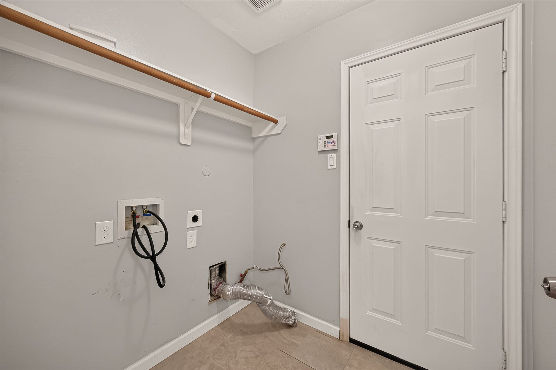 Spacious laundry room featuring washer and dryer hookups, a convenient shelf for storage.