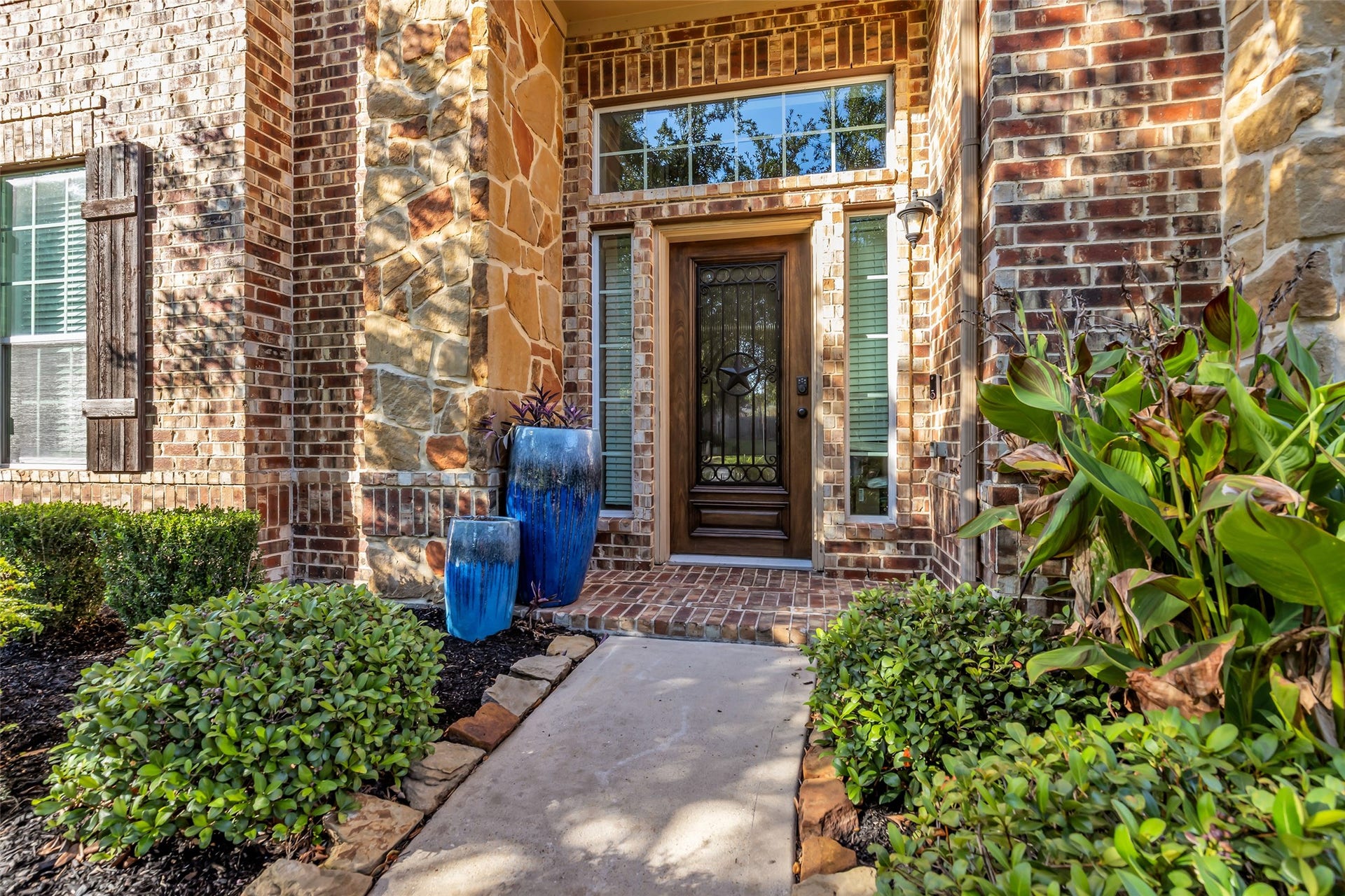 8121 Tranquil Lake Way, Conroe, TX 77385 Charming brick and stone entryway with lush landscaping and elegant double door, creating a warm and inviting welcome.