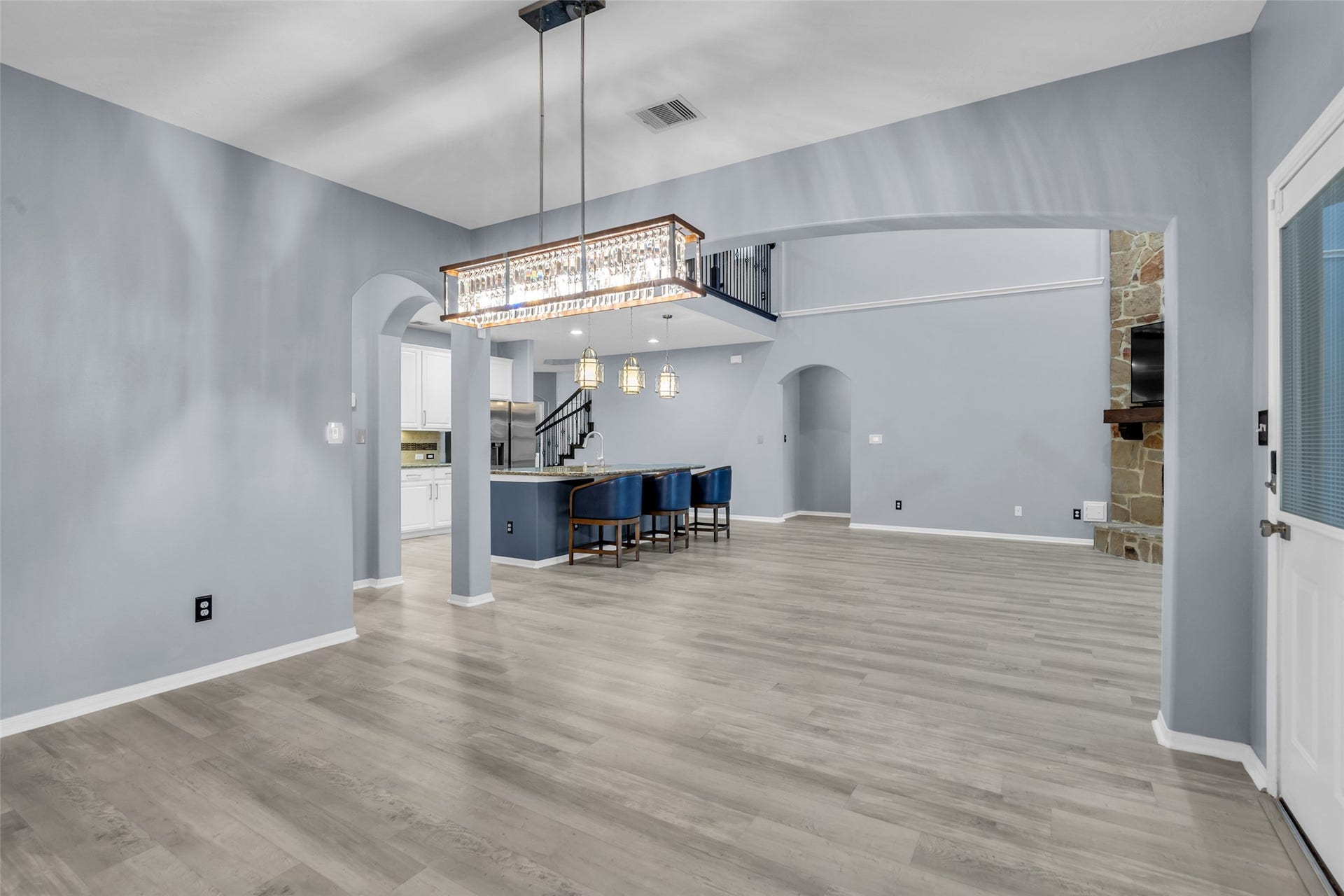 8121 Tranquil Lake Way, Conroe, TX 77385 Breakfast area with spacious open-concept living area featuring elegant light fixtures, modern flooring, and a cozy stone fireplace, seamlessly connecting to a stylish kitchen with a breakfast bar.