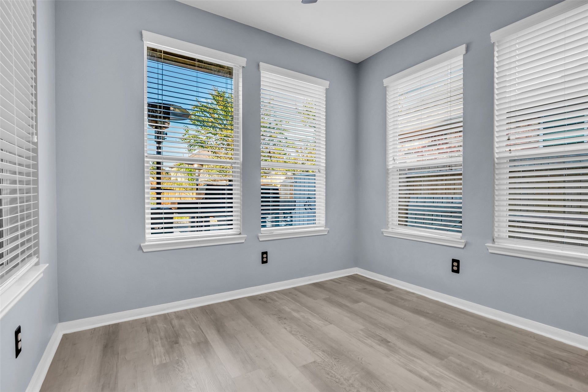 8121 Tranquil Lake Way, Conroe, TX 77385 Bright and airy sunroom featuring large windows with blinds, offering ample natural light and serene views, complemented by elegant LVP flooring.