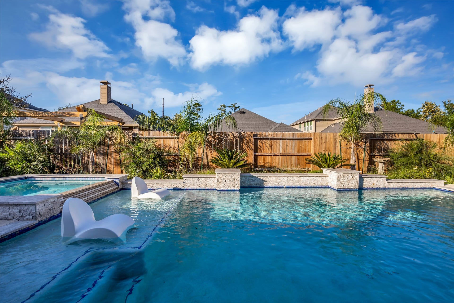 8121 Tranquil Lake Way, Conroe, TX 77385 Experience resort-style living with a stunning backyard oasis featuring a sparkling pool, elegant stone accents, and lush tropical landscaping.