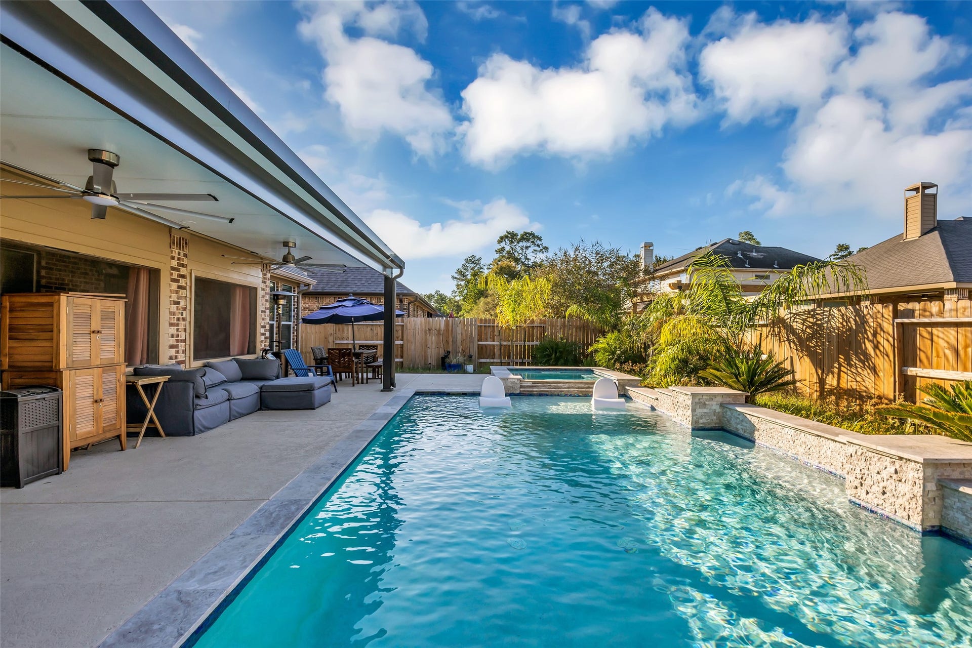 8121 Tranquil Lake Way, Conroe, TX 77385 Experience luxurious outdoor living with a sparkling pool, spacious patio, and stylish seating area perfect for entertaining or relaxing.