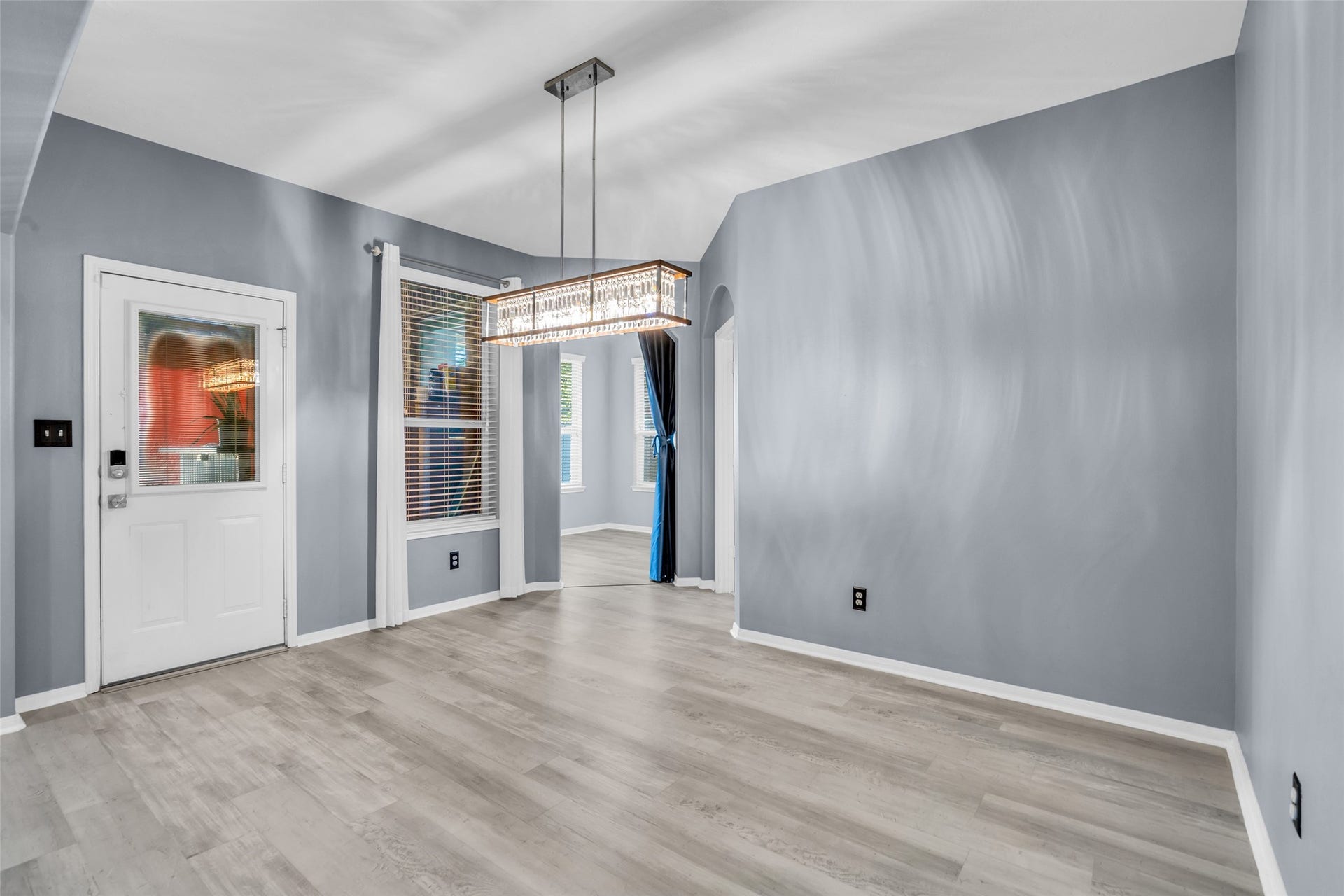 8121 Tranquil Lake Way, Conroe, TX 77385 Elegant breakfast area with sleek laminate flooring, modern chandelier, and abundant natural light through large windows.