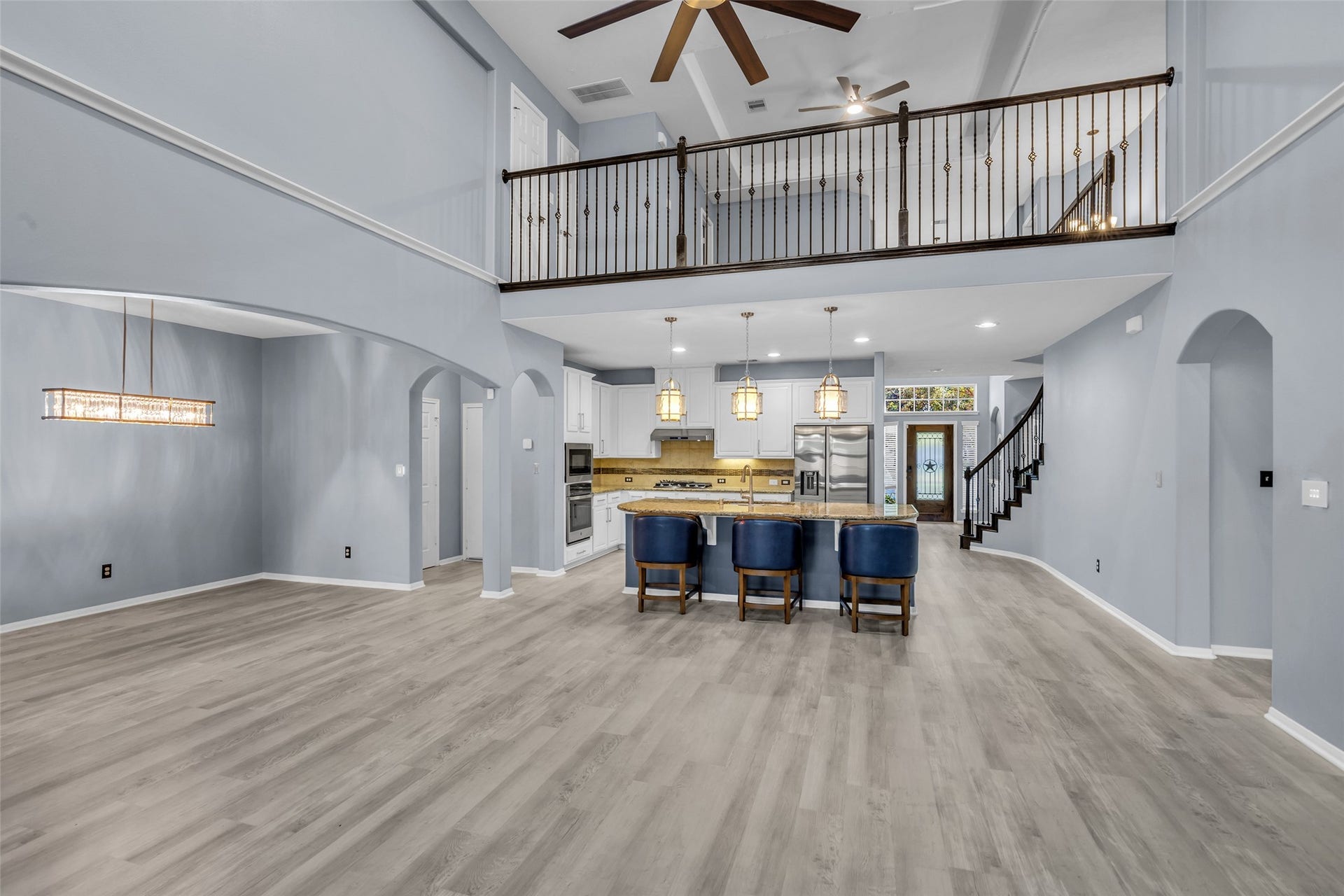 8121 Tranquil Lake Way, Conroe, TX 77385 Stunning open-concept living area with high ceilings, elegant two-story design, and a modern kitchen featuring a large island with seating.