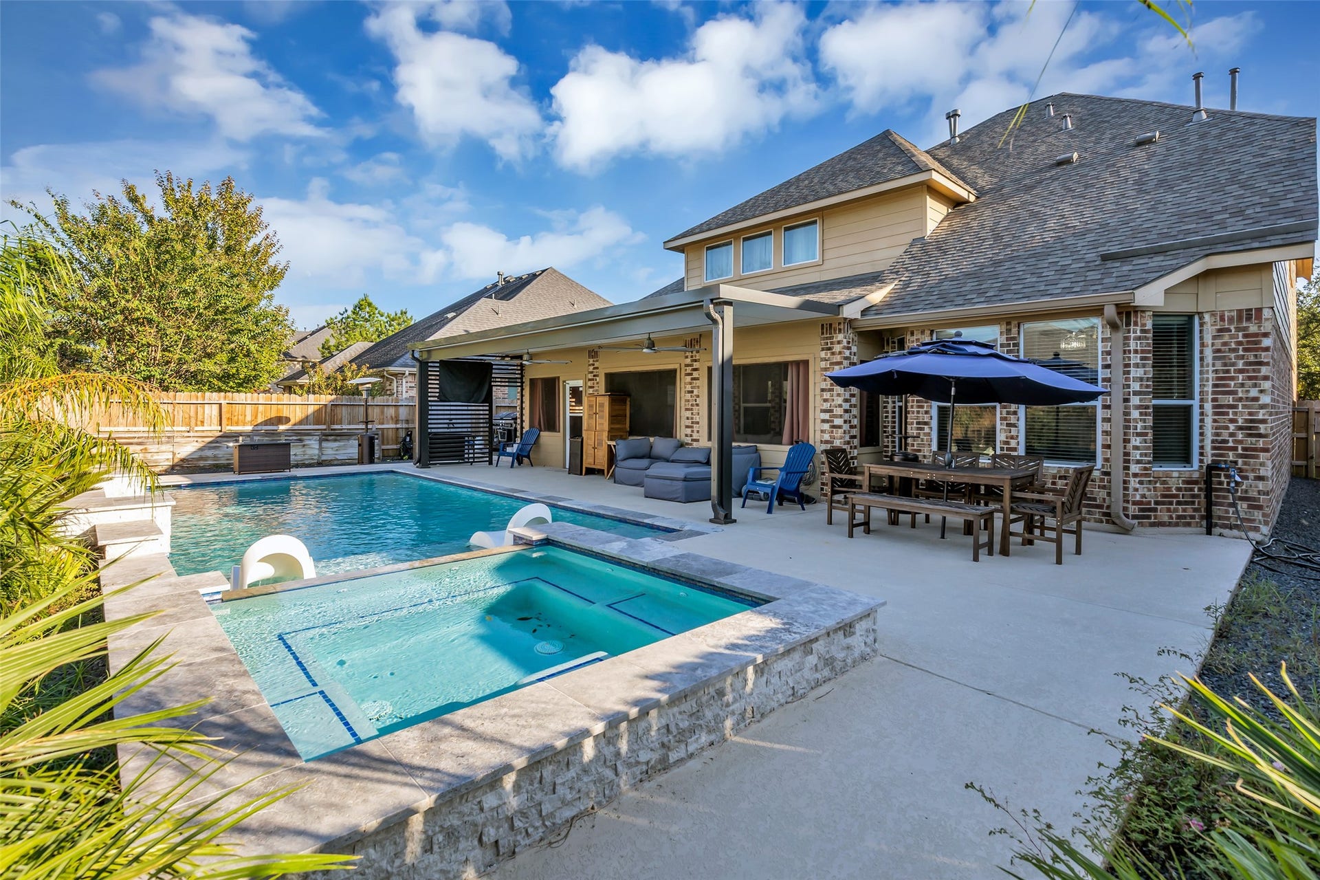 8121 Tranquil Lake Way, Conroe, TX 77385 Stunning backyard oasis featuring a sparkling pool with attached spa, spacious patio with outdoor seating, and a shaded dining area perfect for entertaining.